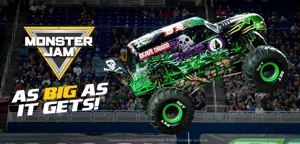 A brightly colored monster truck named Grave Digger decorated with green flames and spooky graphics soars through the air during an arena stunt, with crowds watching in the background. Text on the image reads ‘Monster Jam: As Big As It Gets!’ This image is used to promote the Monster Jam Reading Challenge at the Oconomowoc Public Library.