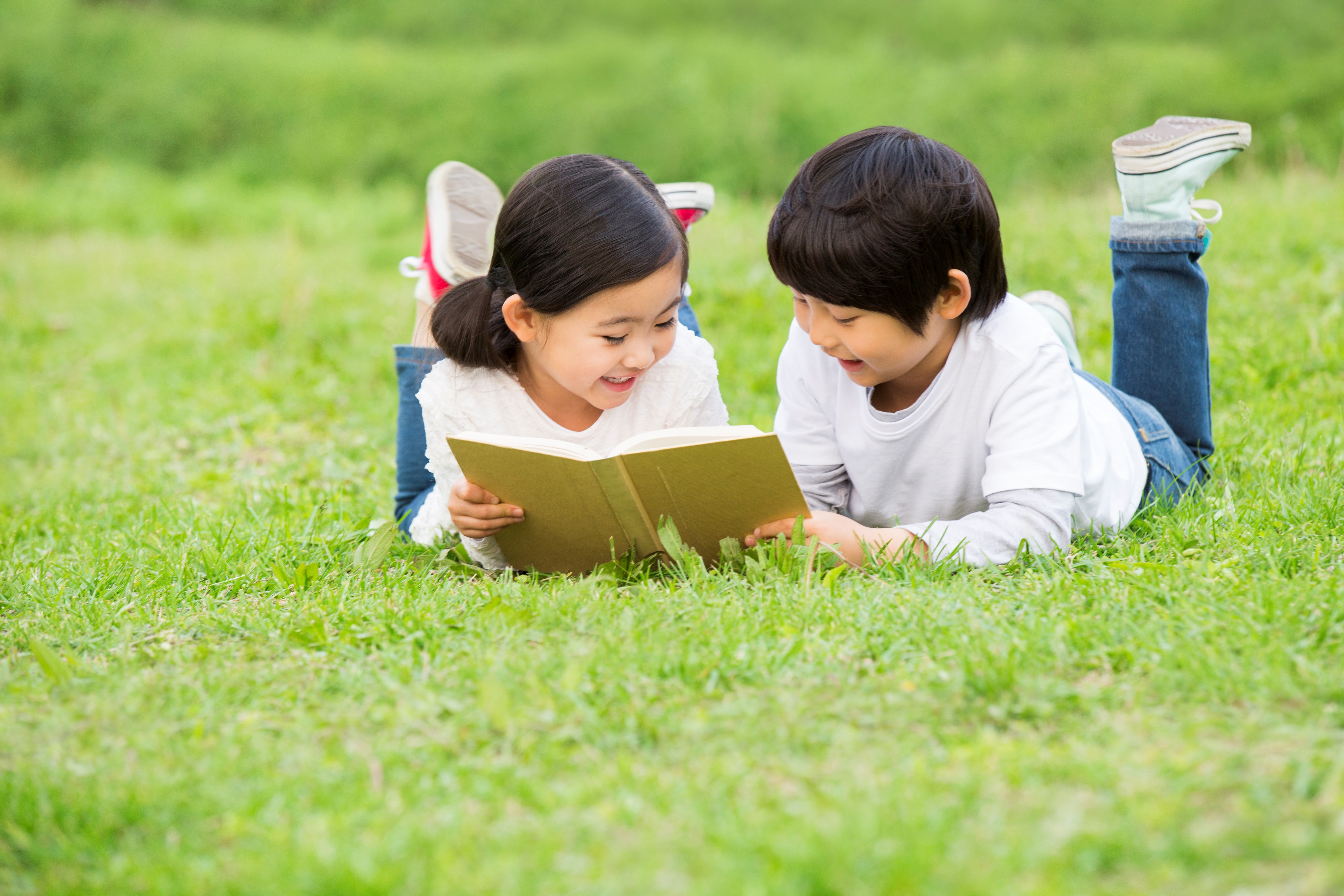 Boy and Girl Reading a Book on the Grass