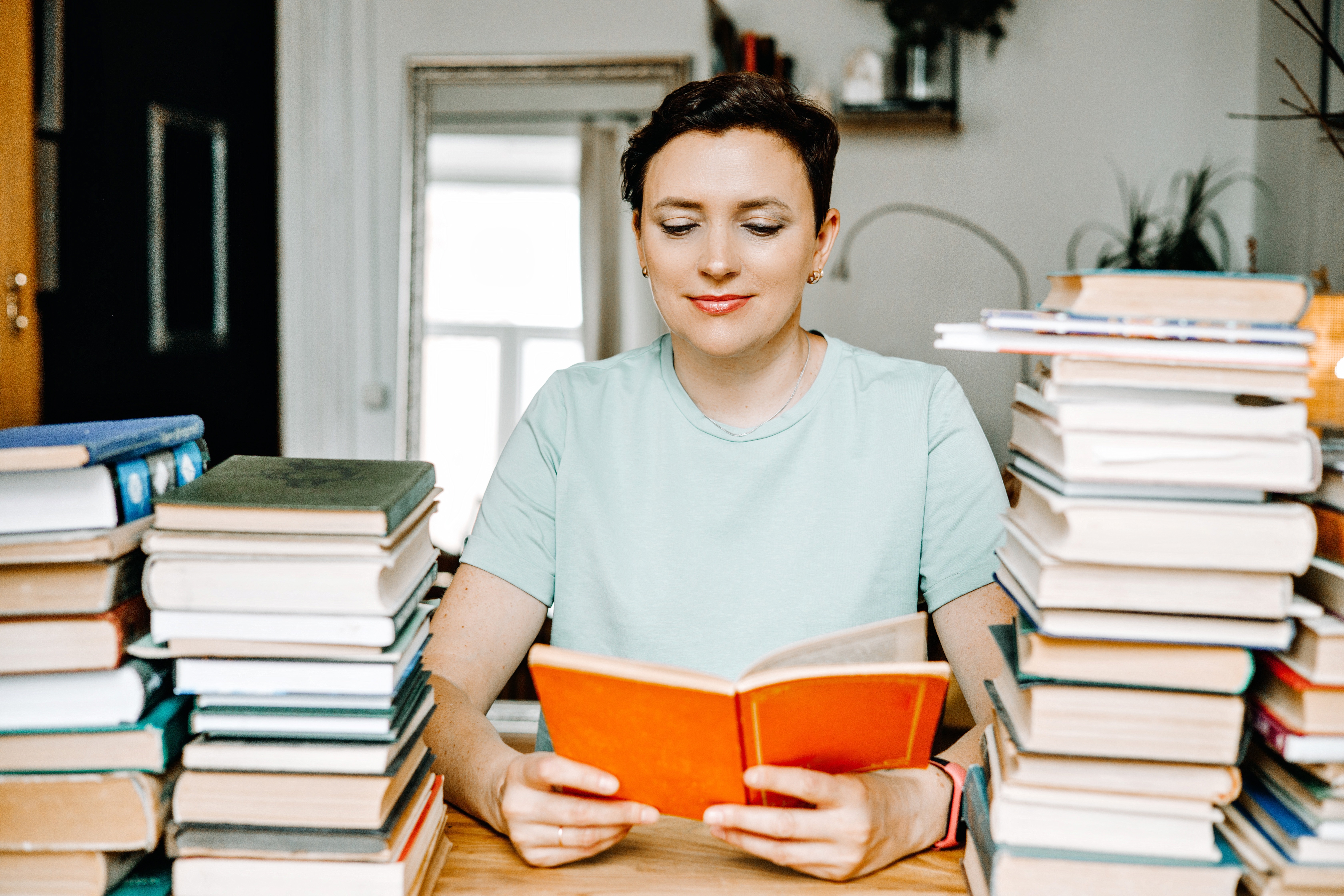 Portrait of Smiling Woman with Stack of Books in Library