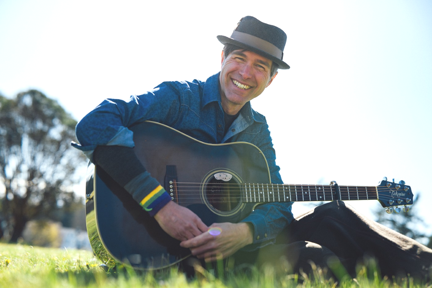 Keeth with guitar in grass outside