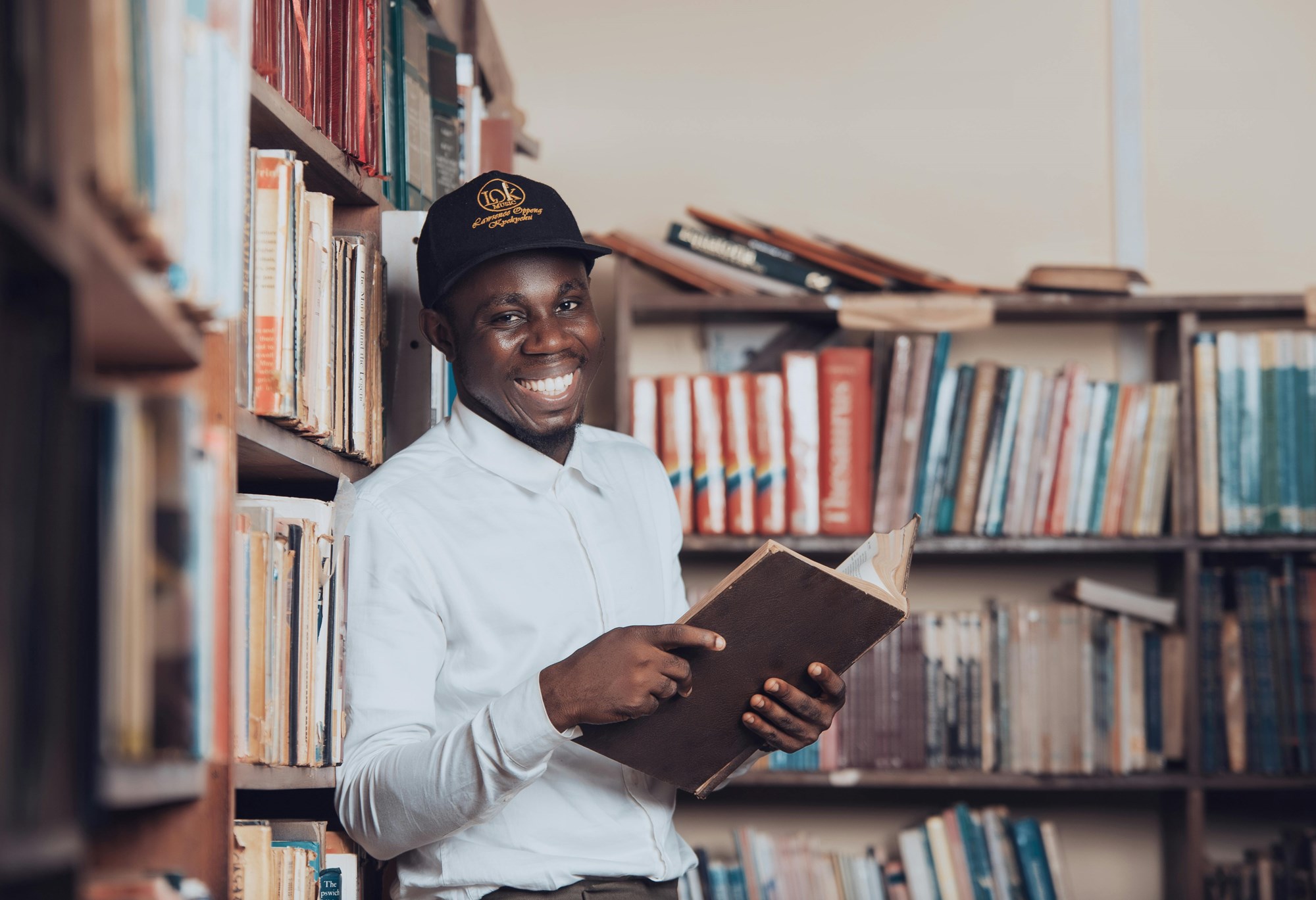 Smiling Man Reading Book in a Ghana Library