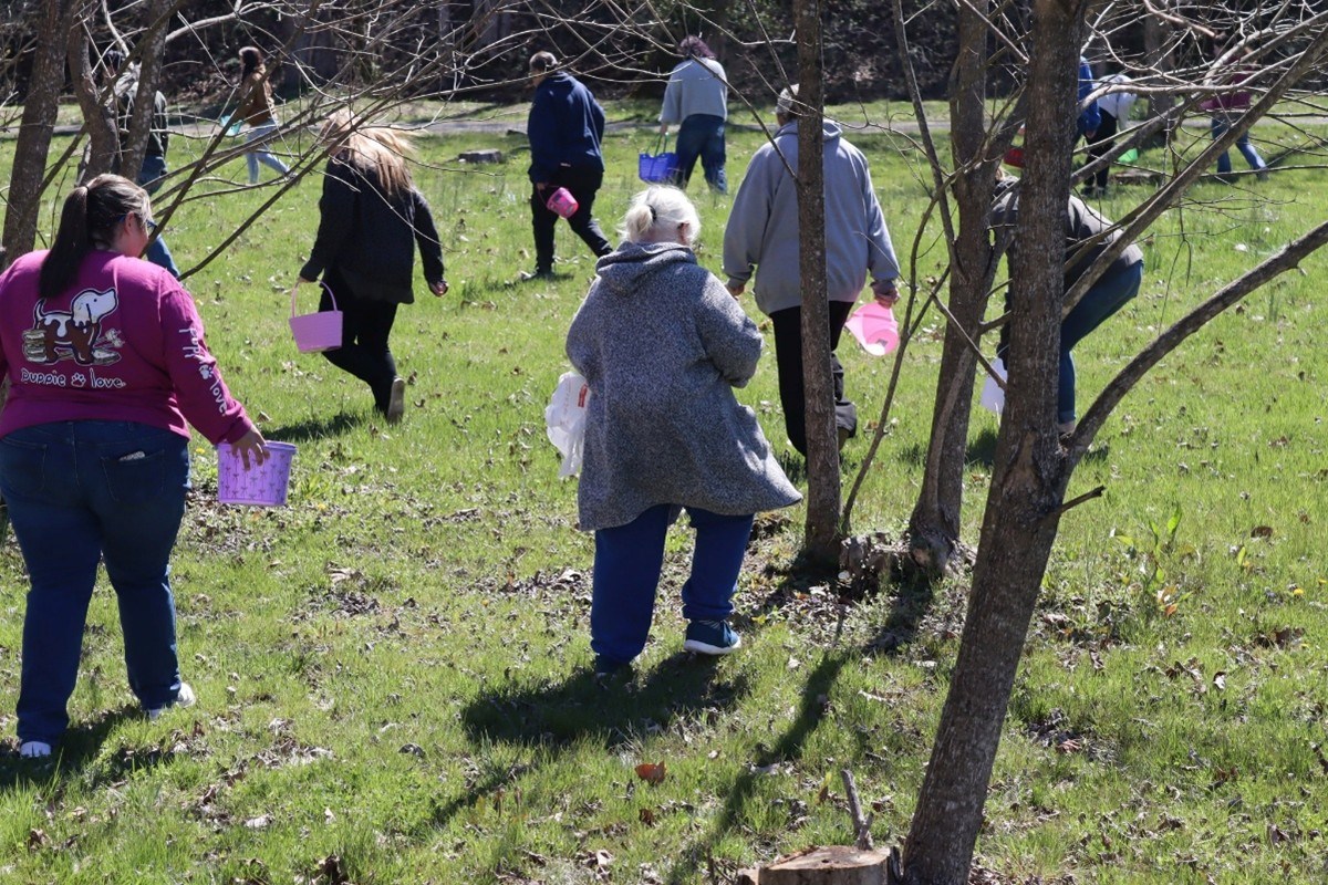 A group of adults in a park on an Easter egg hunt