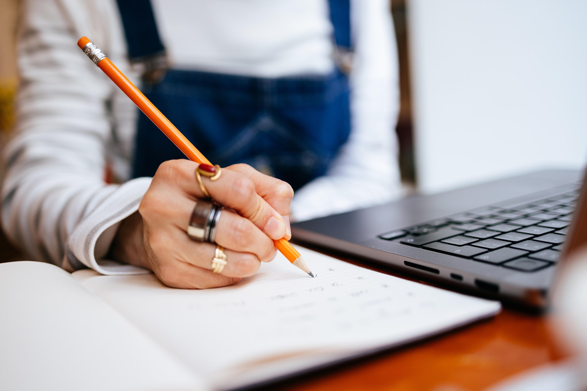 Unrecognized Woman Reading Report on her Laptop and Writing Notes