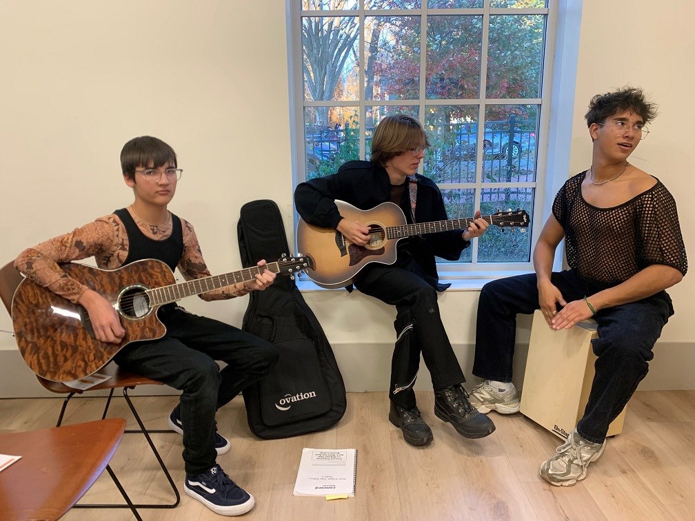 Three teenagers two playing guitar and one playing cajon