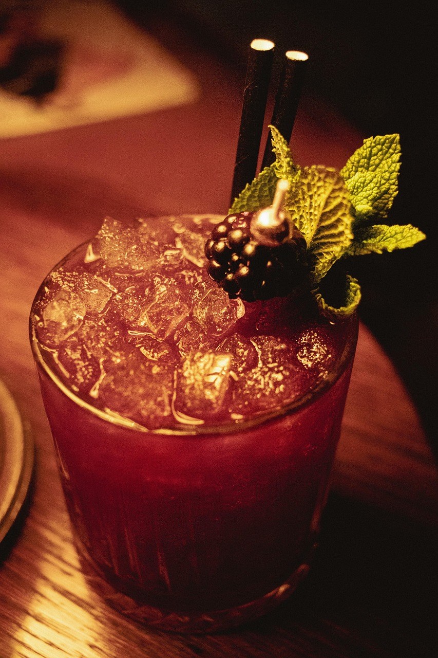 close up of cocktail with mint, ice, and a blackberry