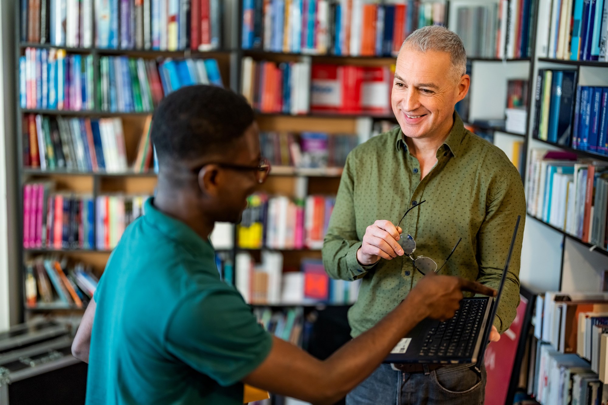 Library Staff Talking in Front of Bookshelves