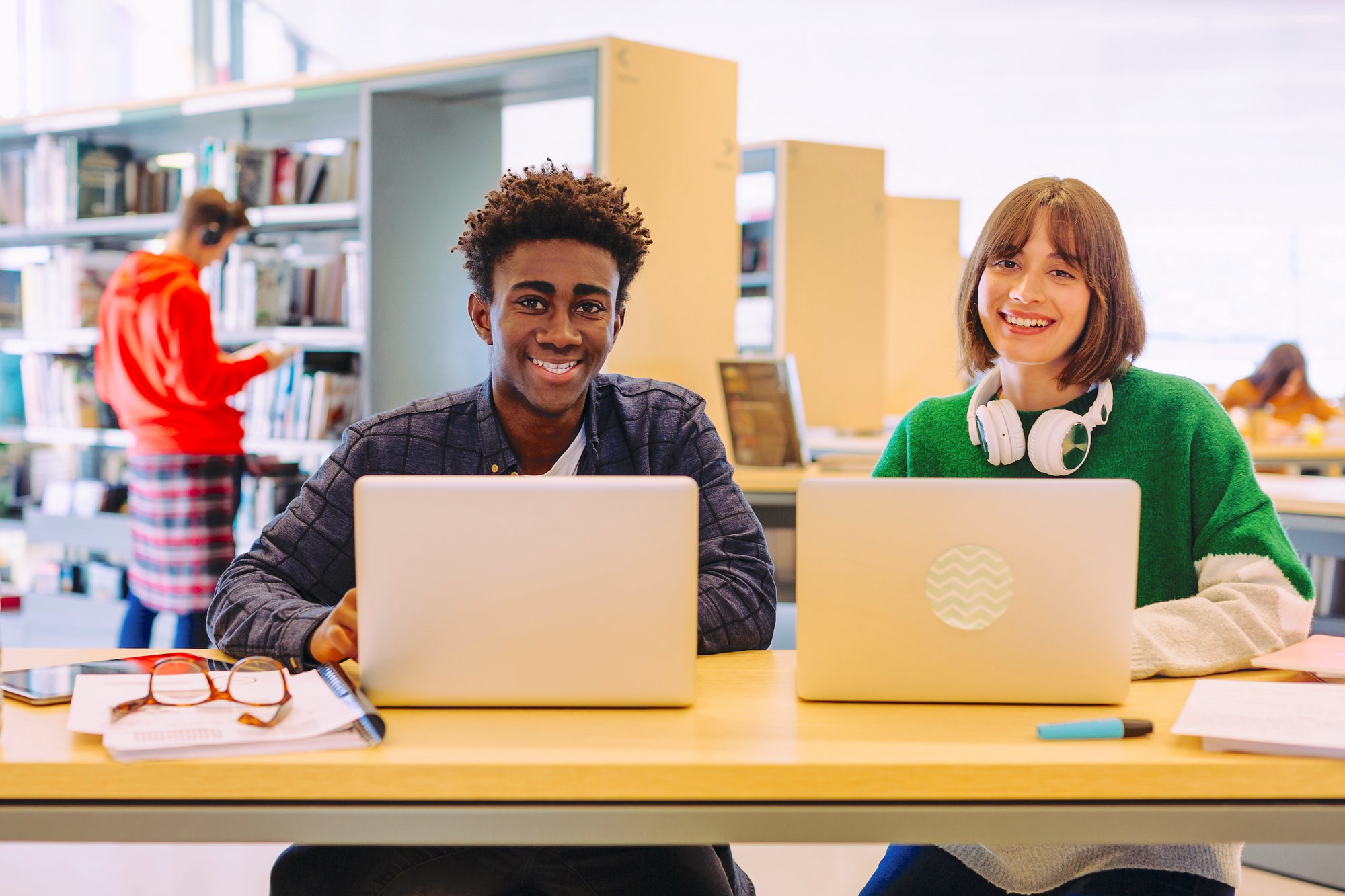 Two Teens Using Laptops in Library