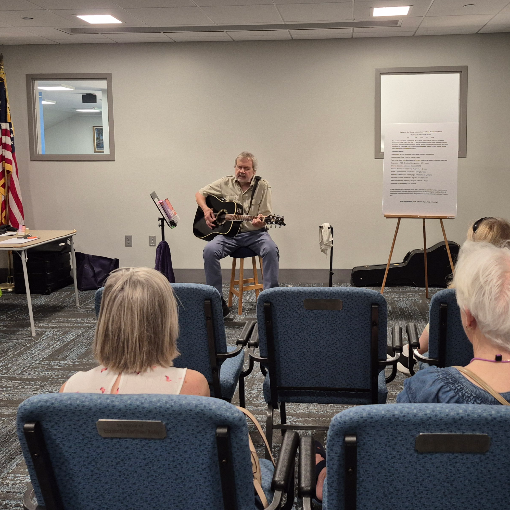 Michael Skinner playing guitar and singing in the Meeting Room of the library.