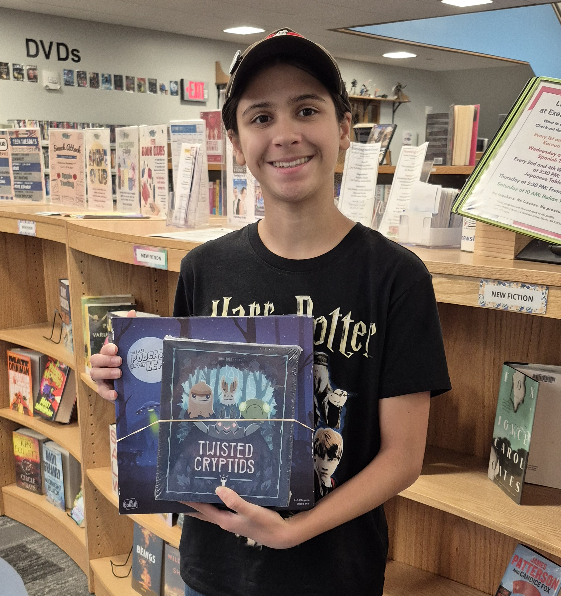 A prize winner posing with their cryptid-themed board games.
