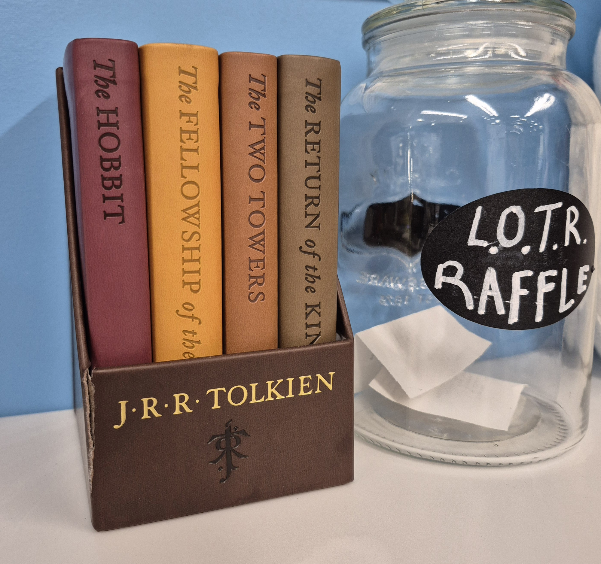 The leather bound copies of the books sitting next to the jar filled with entries for the raffle.