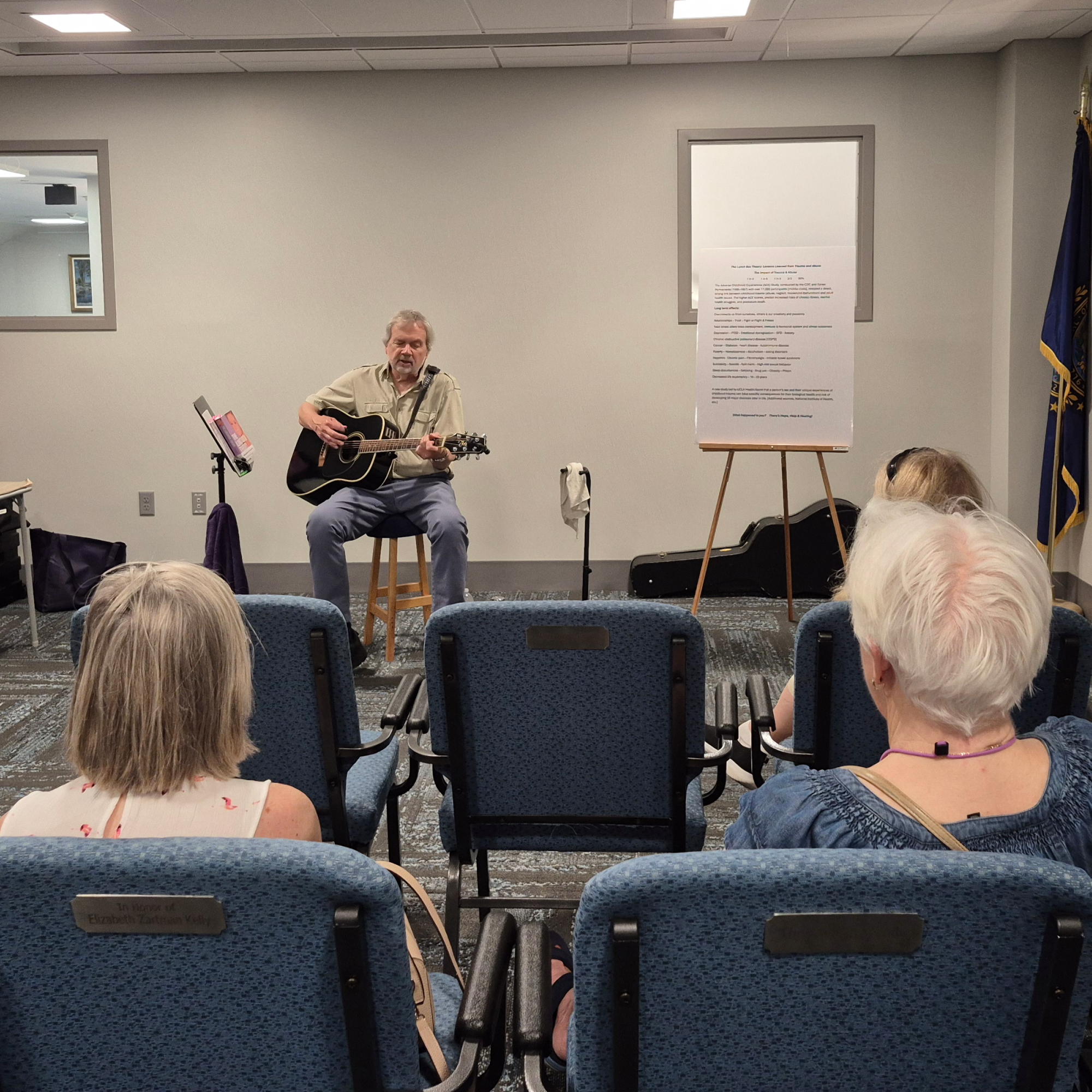 Michael Skinner playing guitar and singing in the Meeting Room of the library.