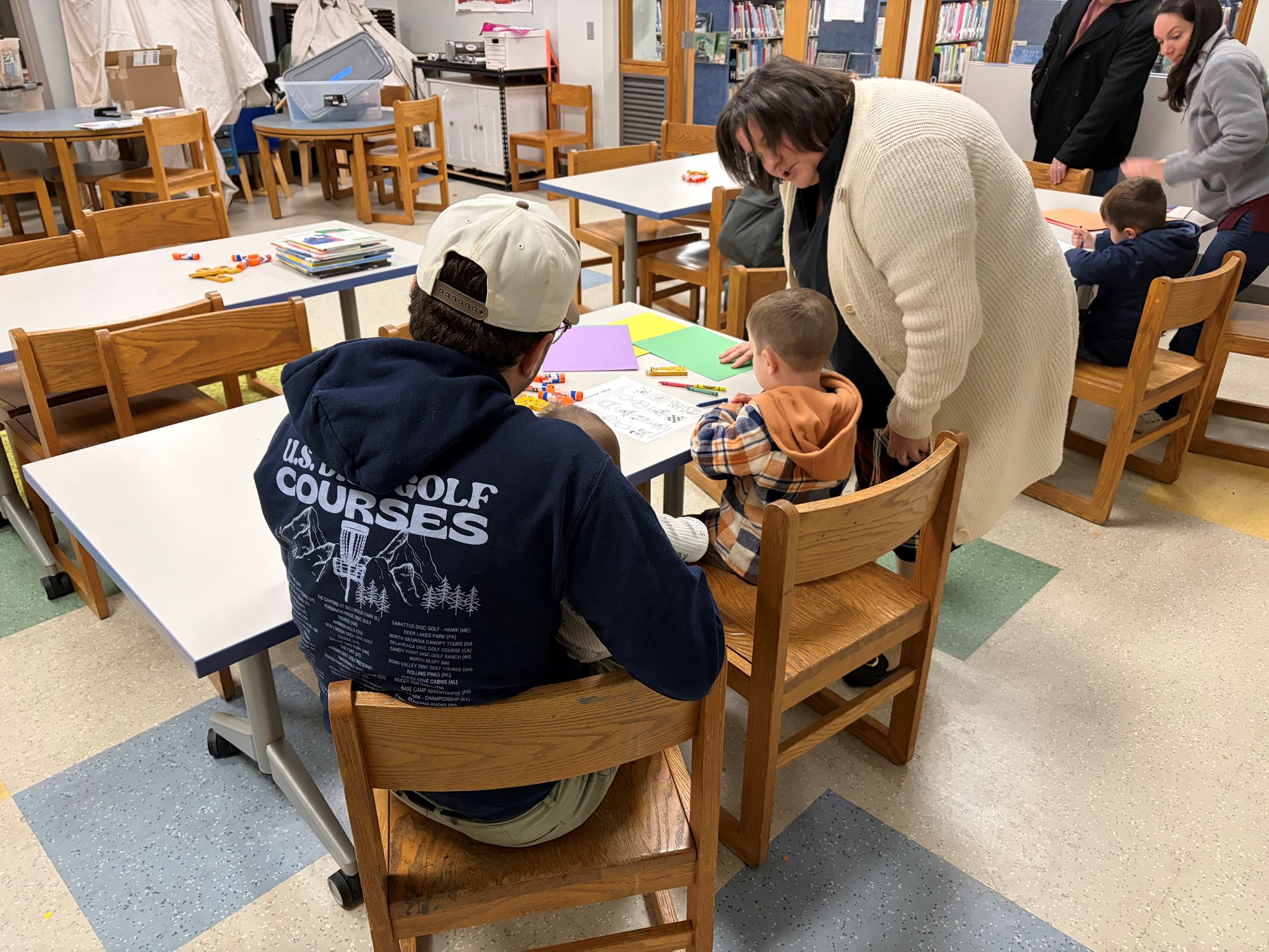 Director Julia checking in with a family completing one of the Sesame Street Digital Workshop activities in the Craft Room of the Children's Room.
