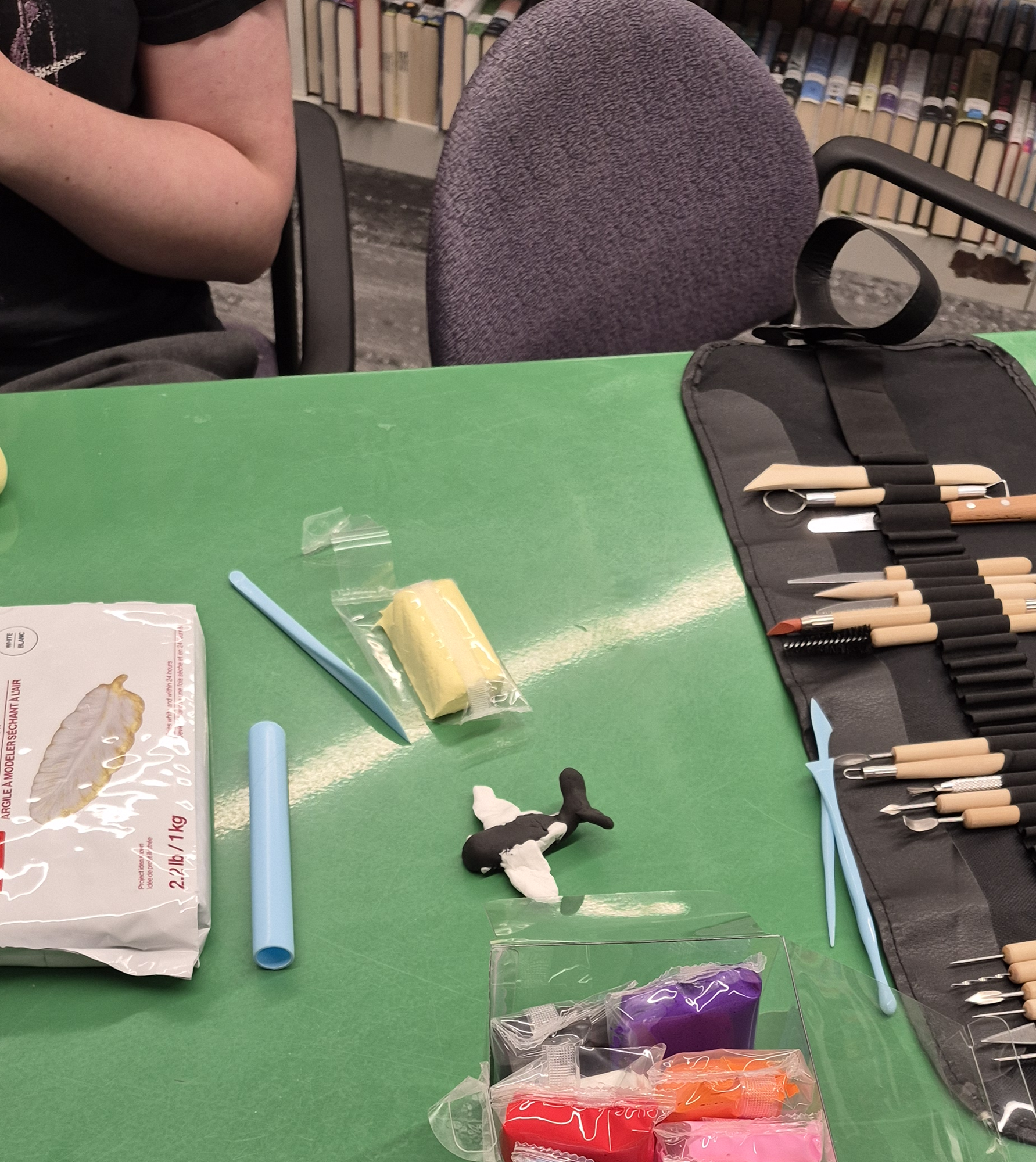 Clay and other creature-making supplies on a green table in the Teen Scene.