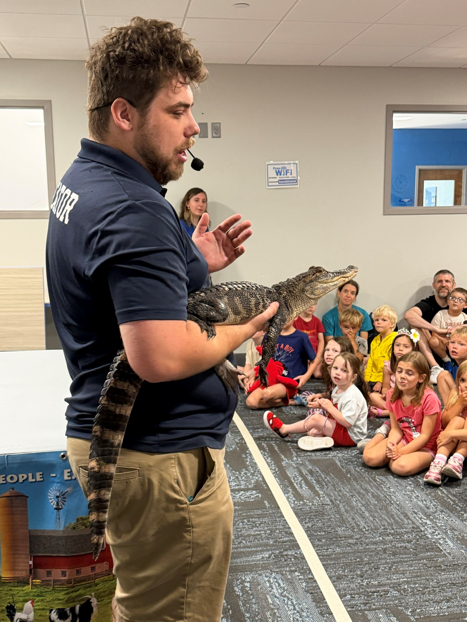 A Wildlife Encounters team member holding a baby crocodile in the Meeting Room.