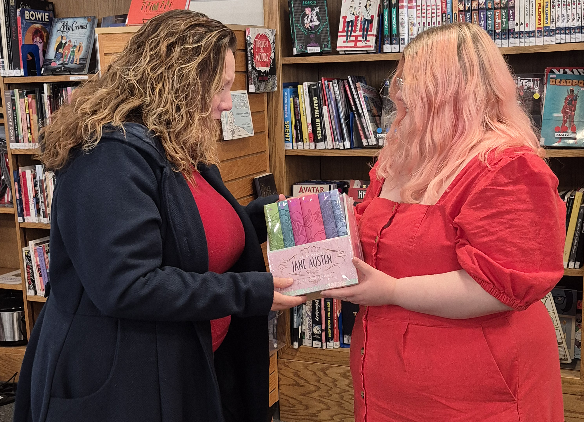 The winner and librarian Loren posing looking at the set of Jane Austen's books won.