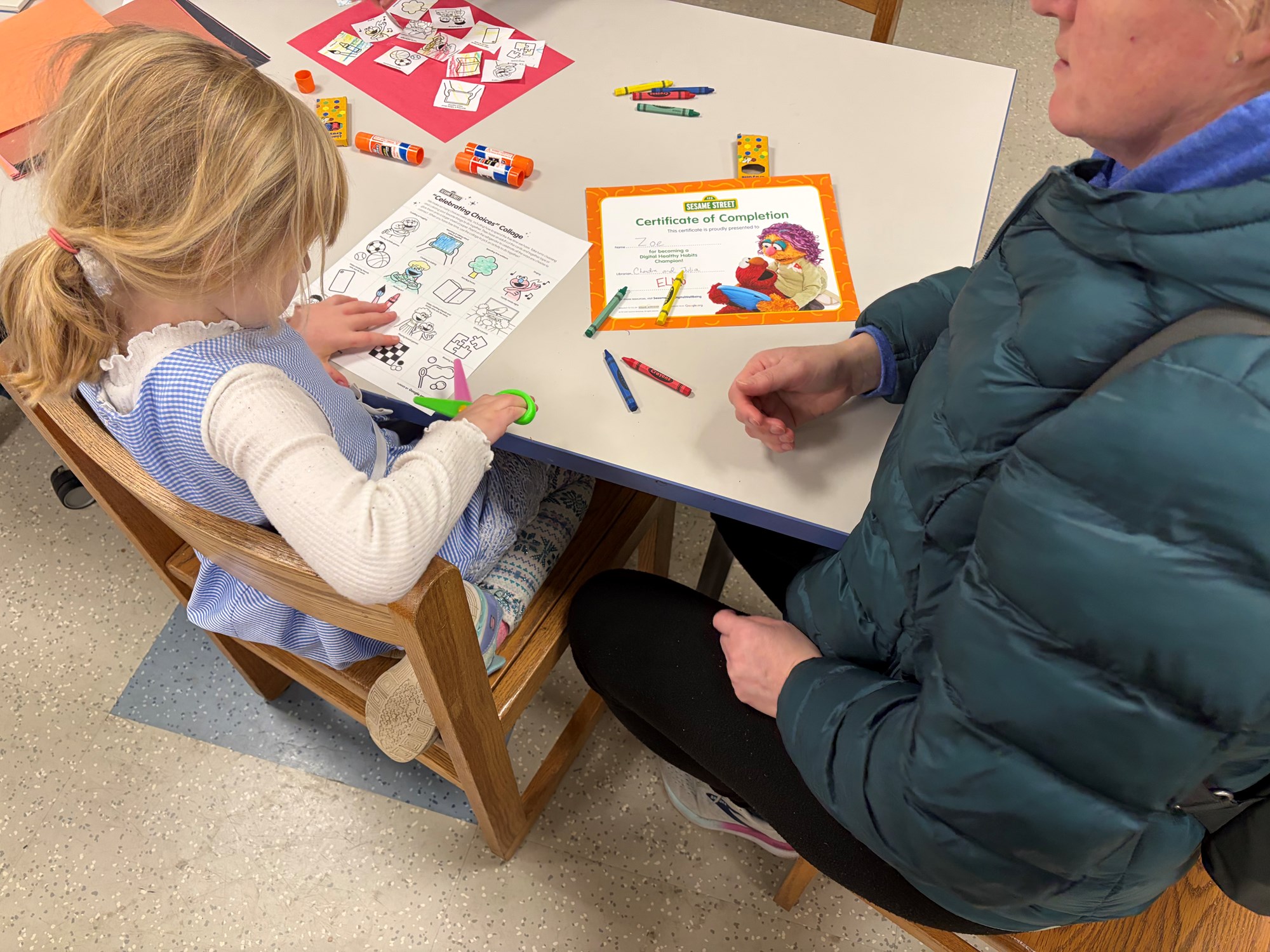 A family completing one of the Sesame Street Digital Workshop activities in the Craft Room of the Children's Room.