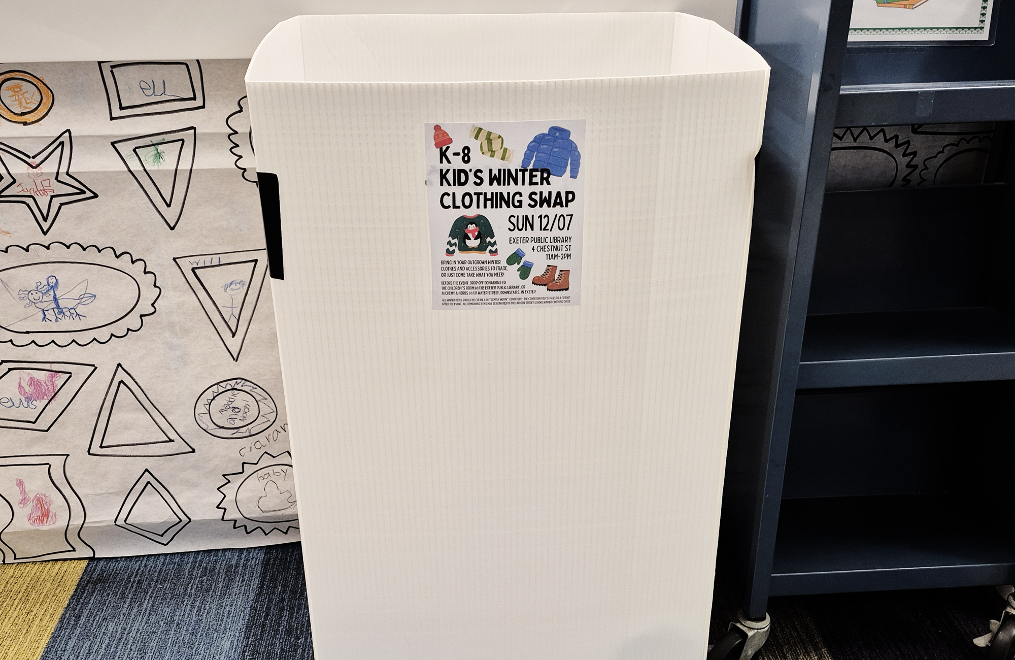 The donation box for the Kid's Winter Clothing Swap in front of the desk in the Children's Room. 