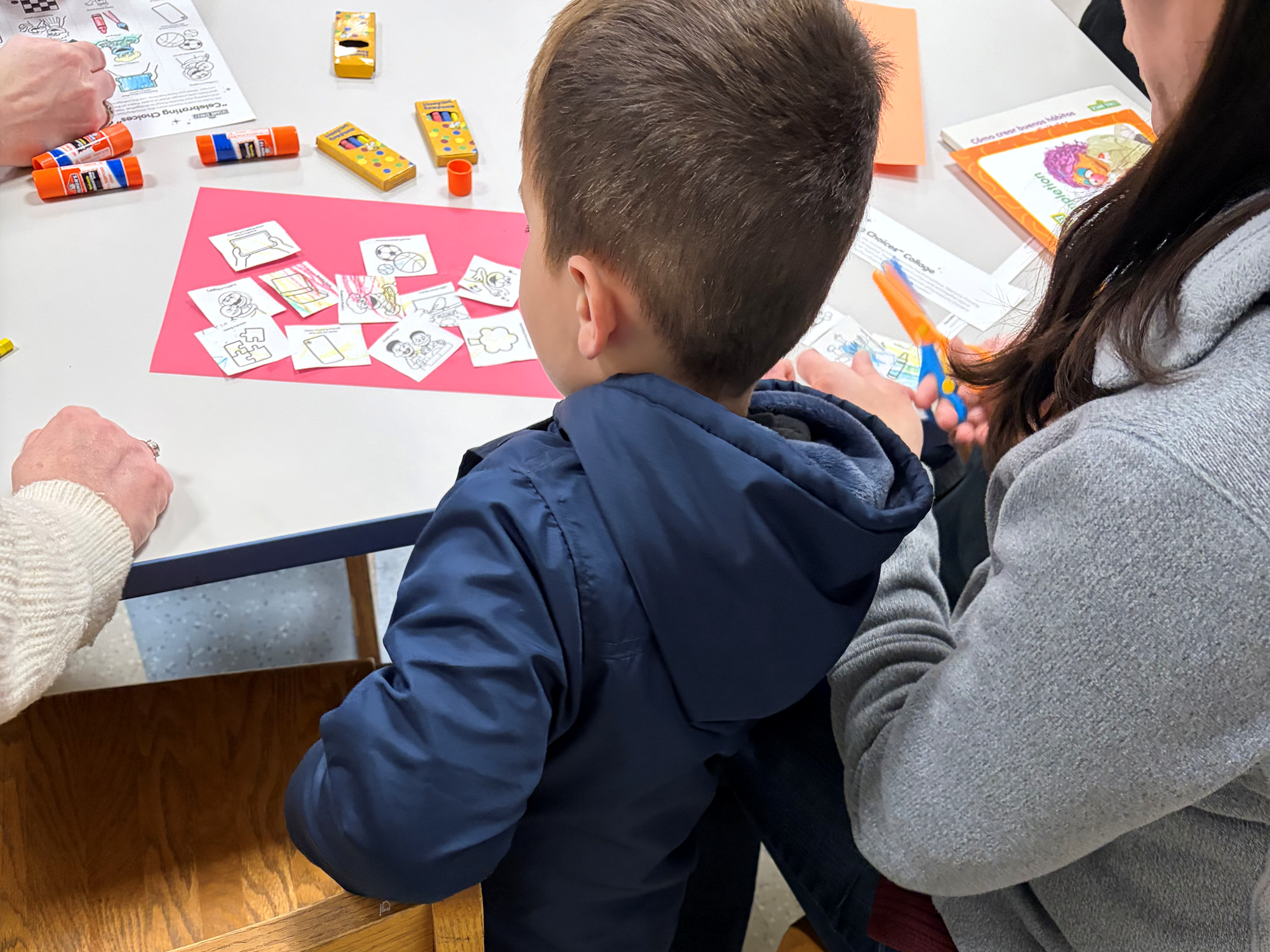 A family completing one of the Sesame Street Digital Workshop activities in the Craft Room of the Children's Room.