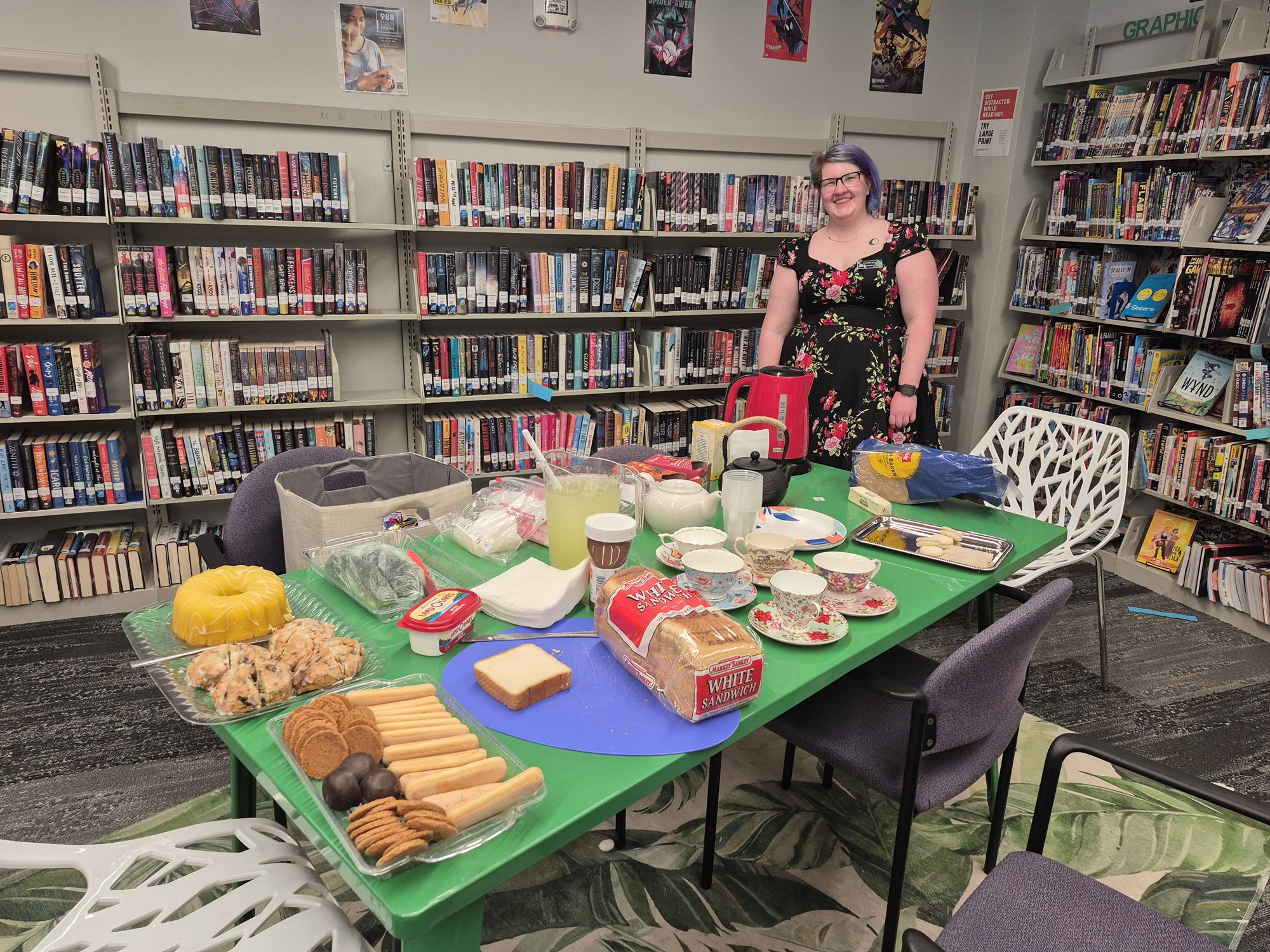 Librarian Chandra standing by the table of tea and treats for the party in the Teen Scene.