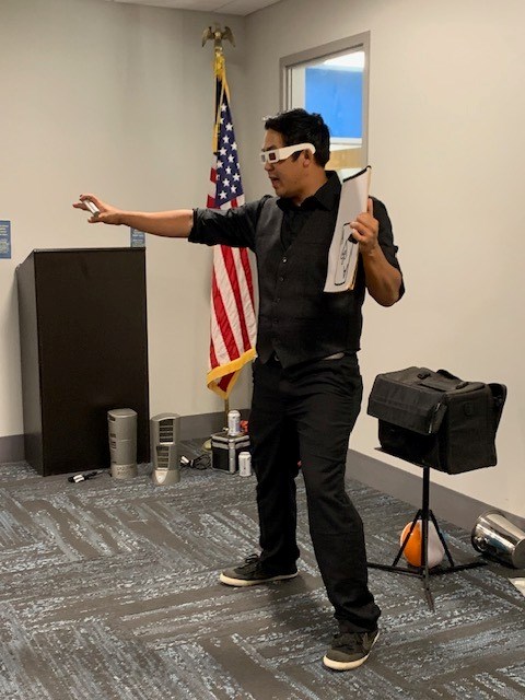 Norman Ng performing a magic trick in the Meeting Room of the library.