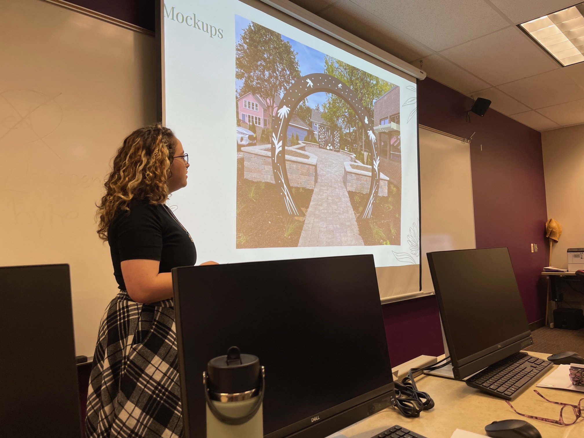 Student standing in front of a screen displaying a mock-up of the design.