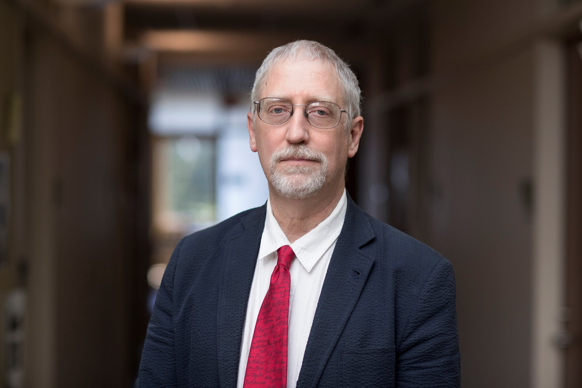 white man in a dark suit and red tie