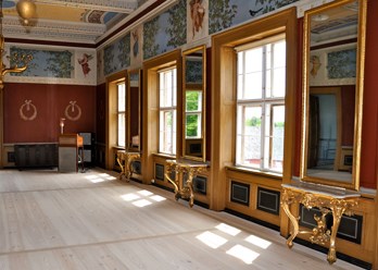 ornate golden pier tables in a large room with windows