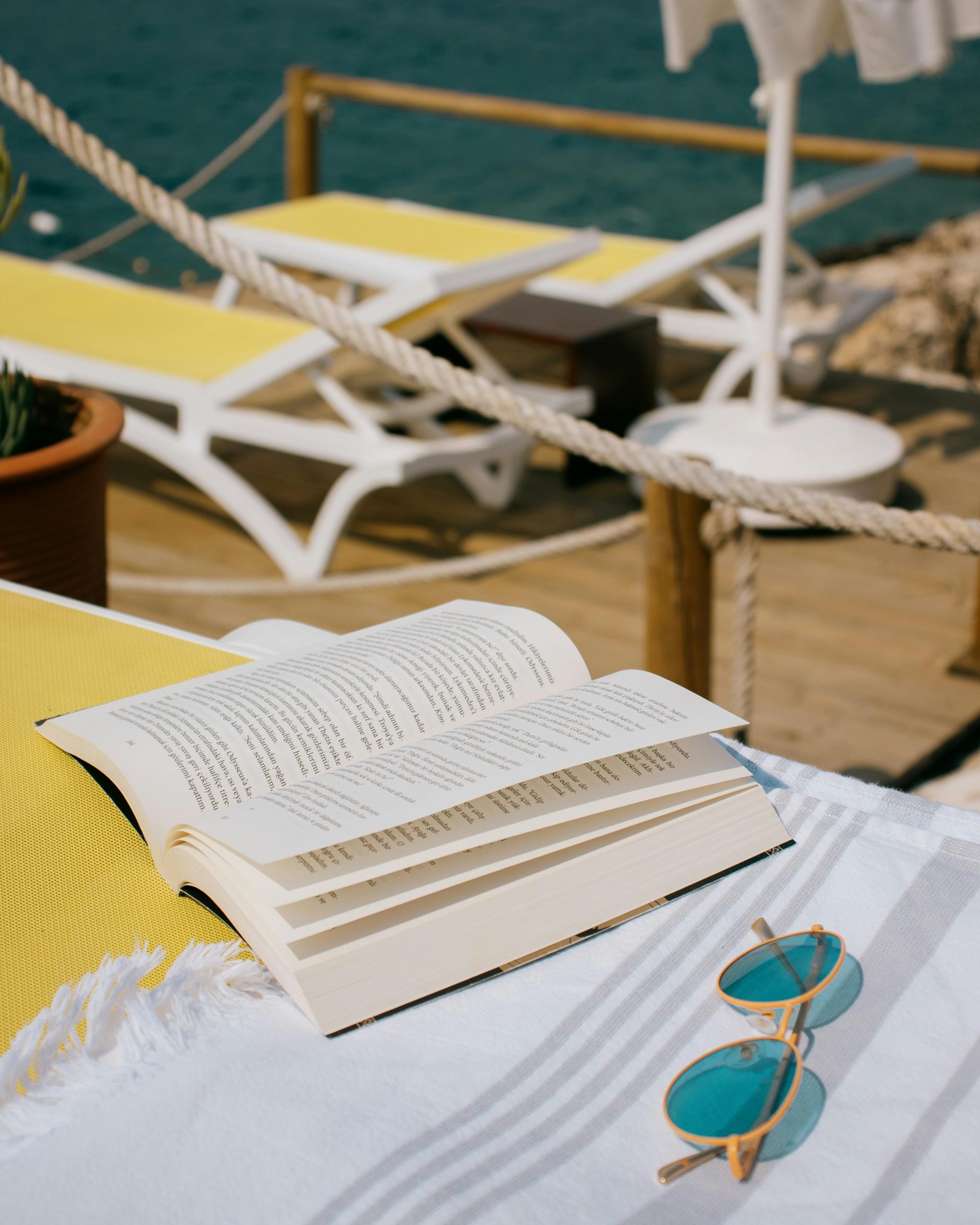 An Open Book and Sunglasses on a Seaside Lounge Chair