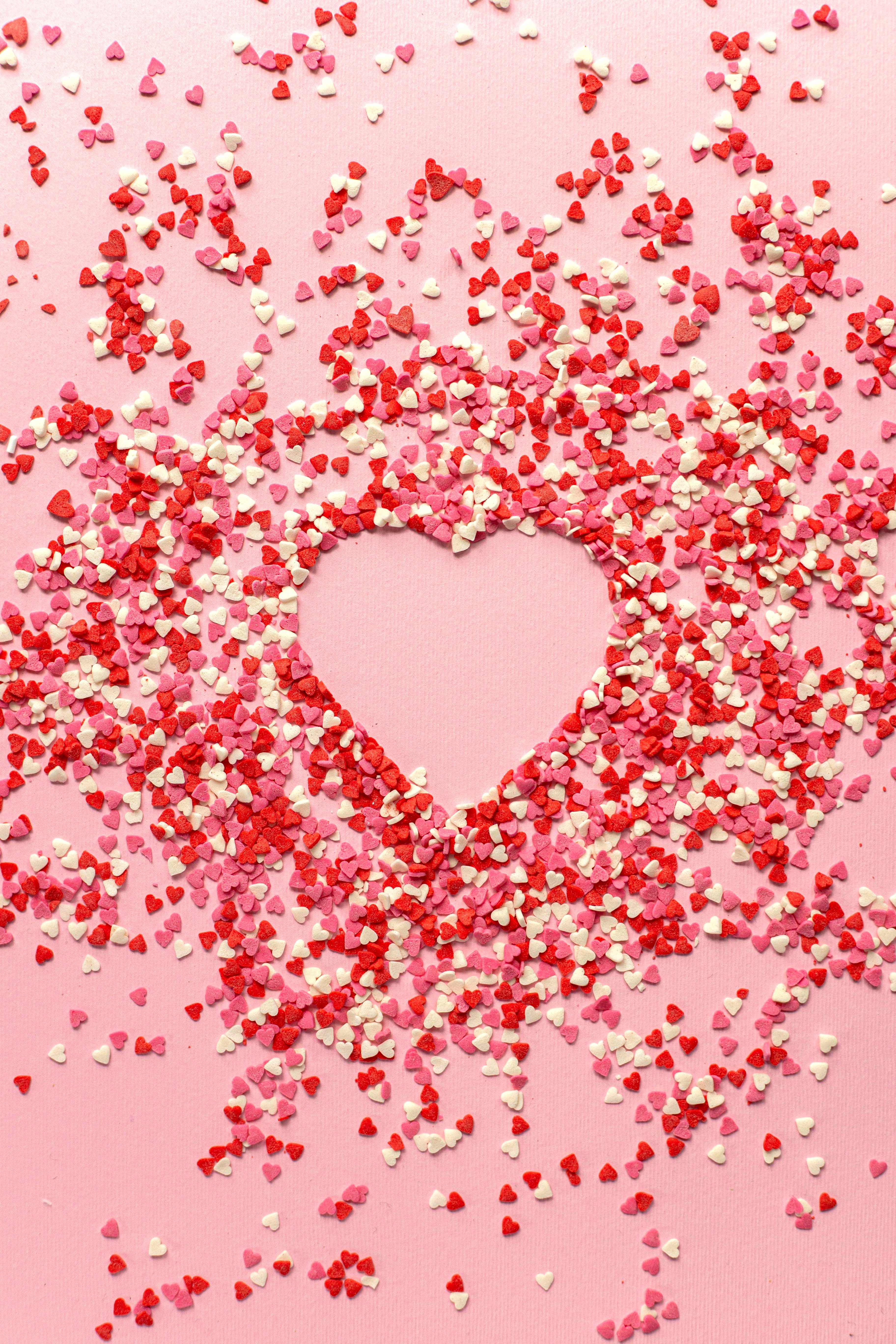 Paper Confetti in Heart Shape on Pink Background