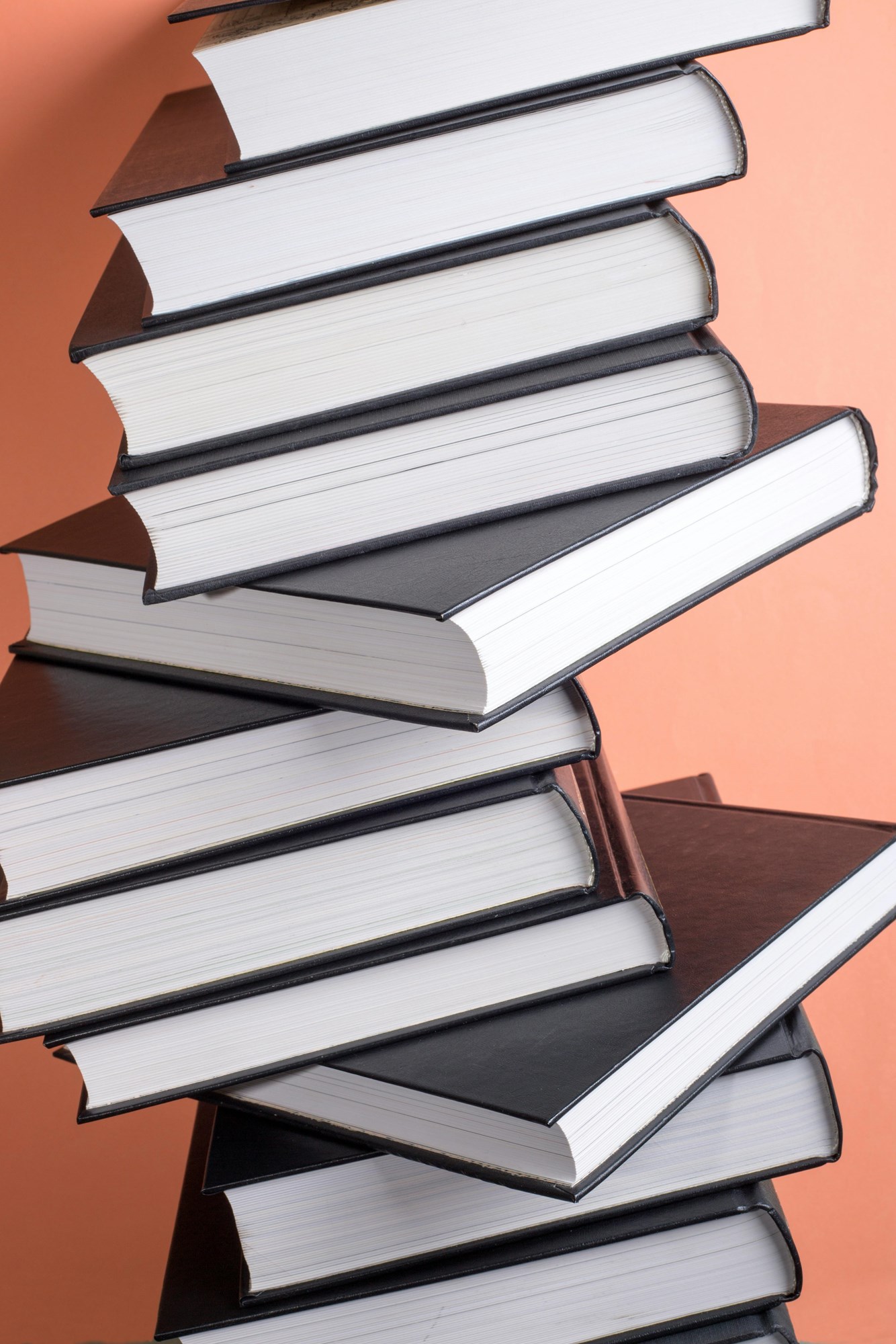 Stack of Hardback Books Against Peach Background