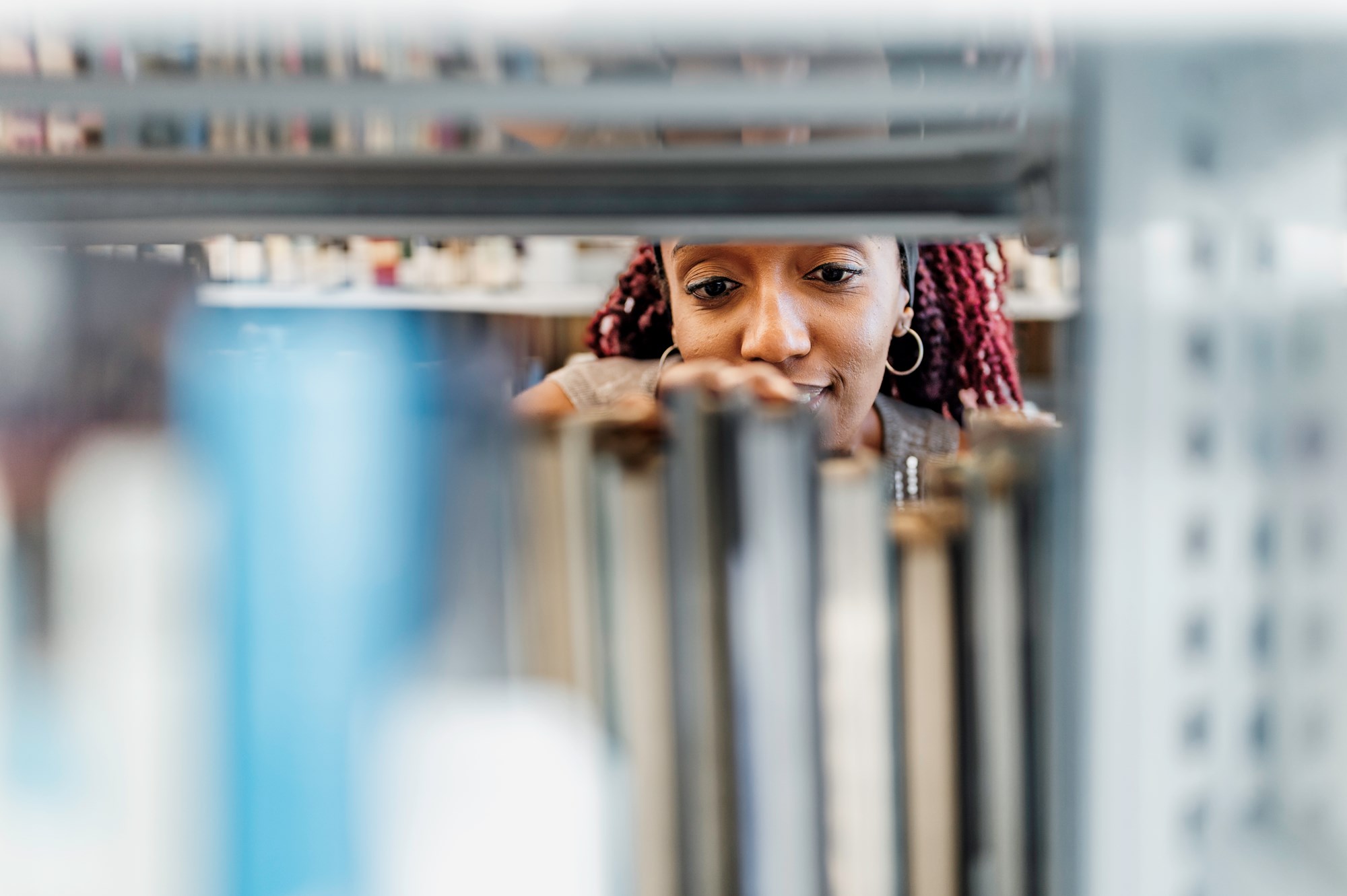 Young Woman Browses Through Stacks Of A Library In A University Campus
