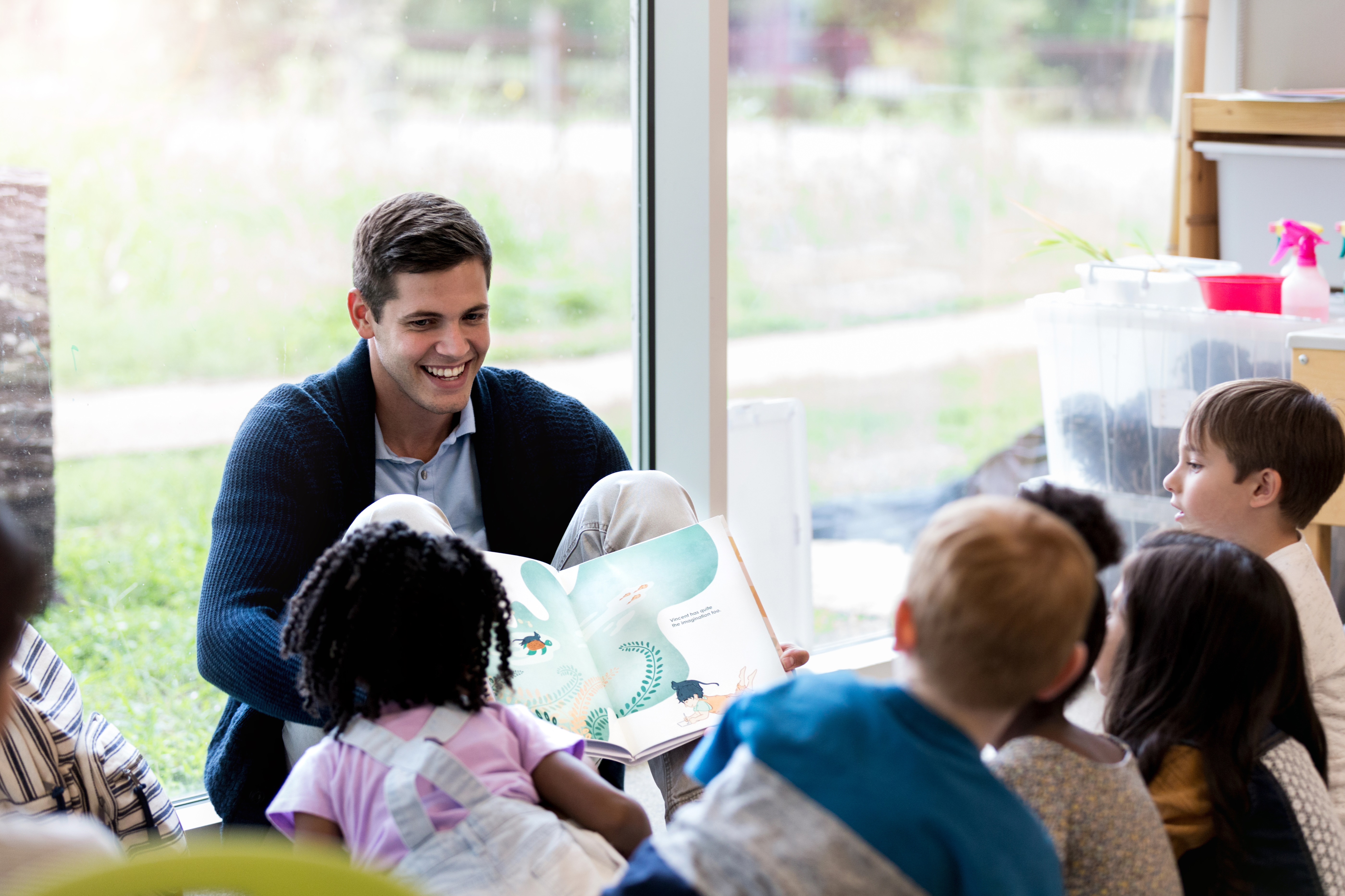 Cheerful Male Librarian Reads Book to Storytime Group