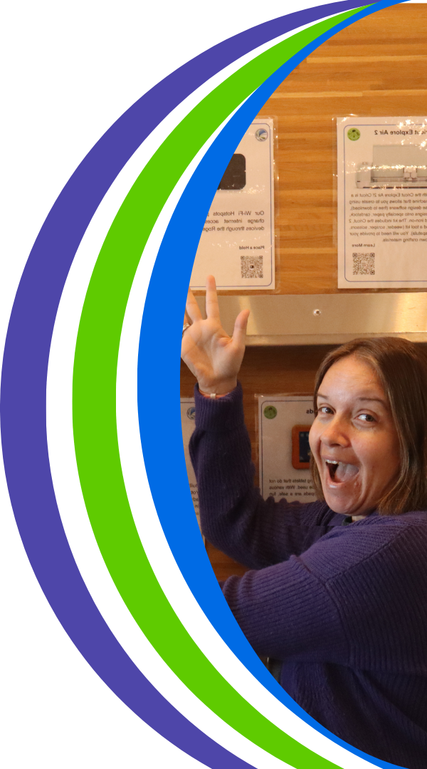 Photo of Melissa posing excitedly in front of the library of things wall. 