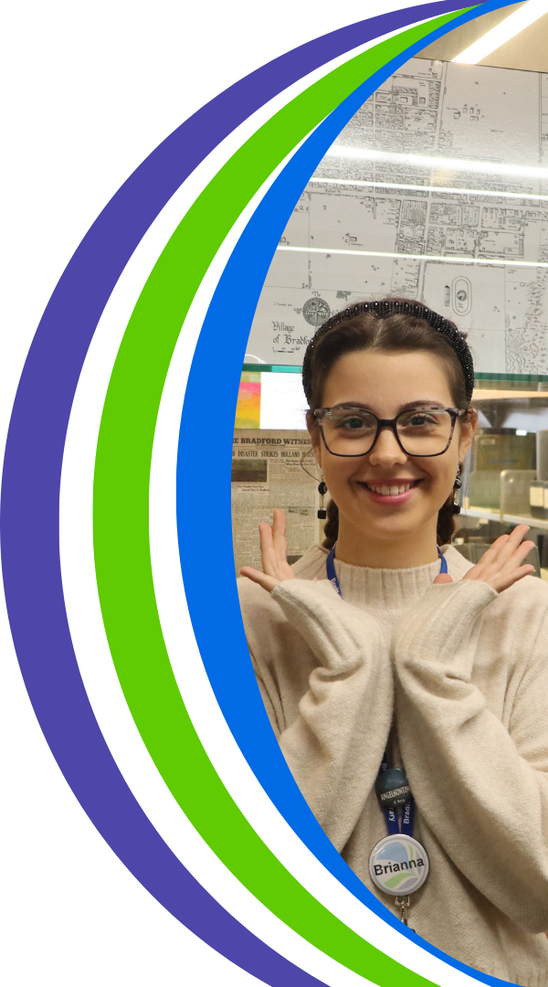 Photo of Brianna smiling in front of the local history room. 