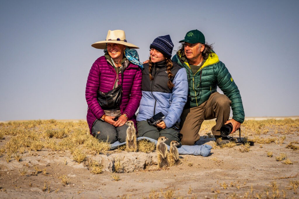 Isa Catto, Daniel Shaw, and Fiona posing behind a family of meerkats