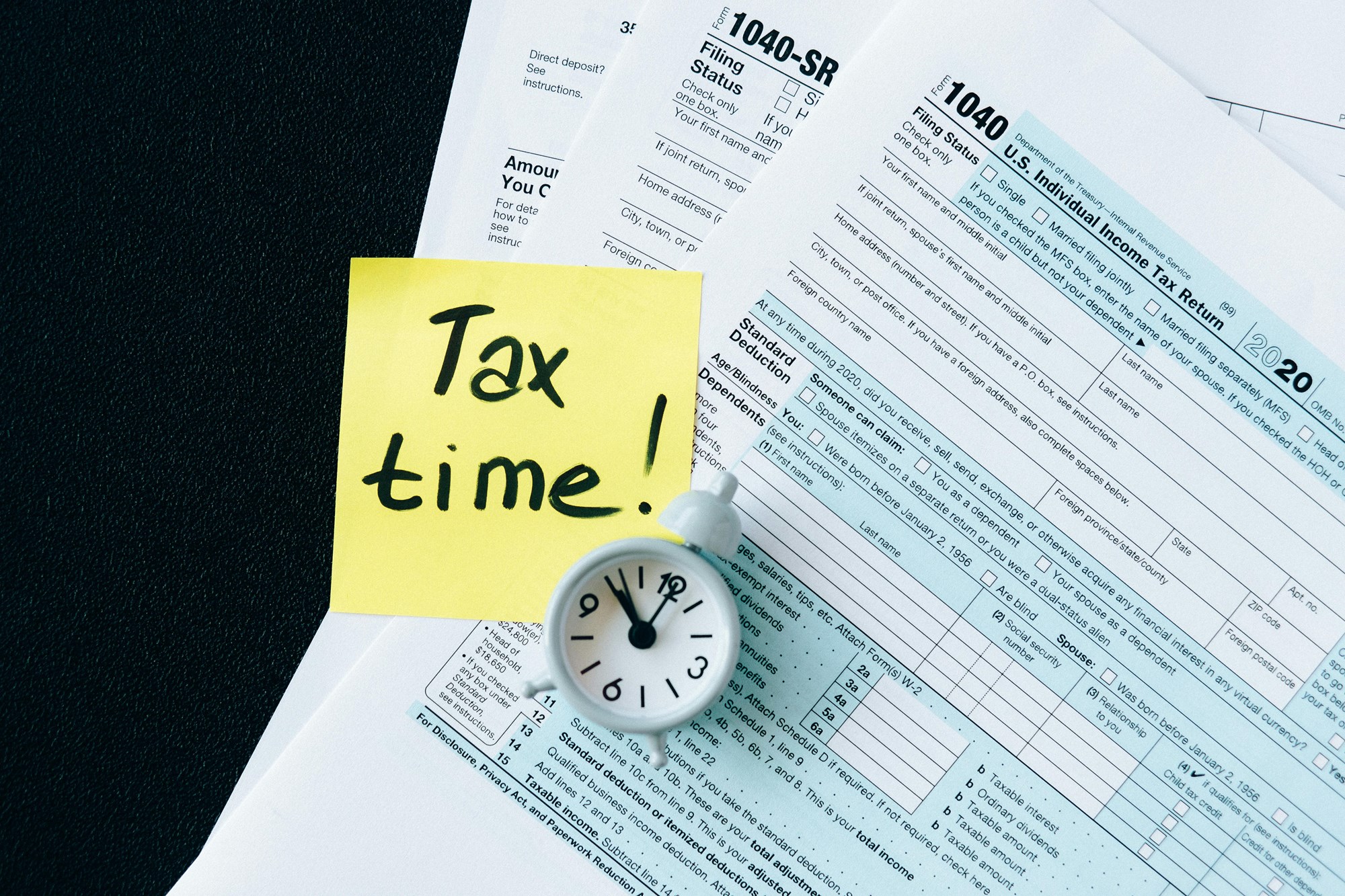 1040 personal tax forms with a yellow sticky note saying "Tax time!'