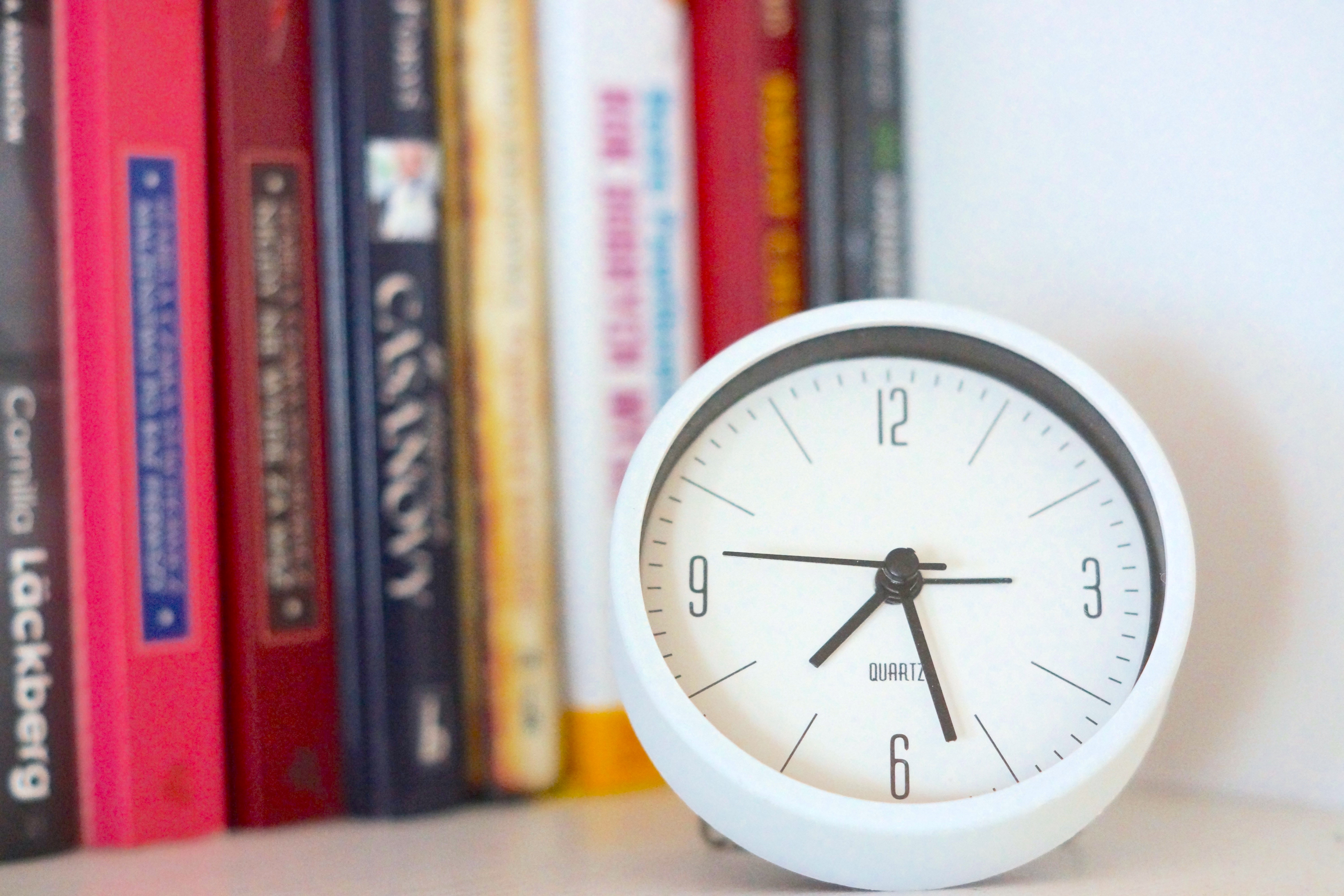 White Table Clock and Books on Bookshelf