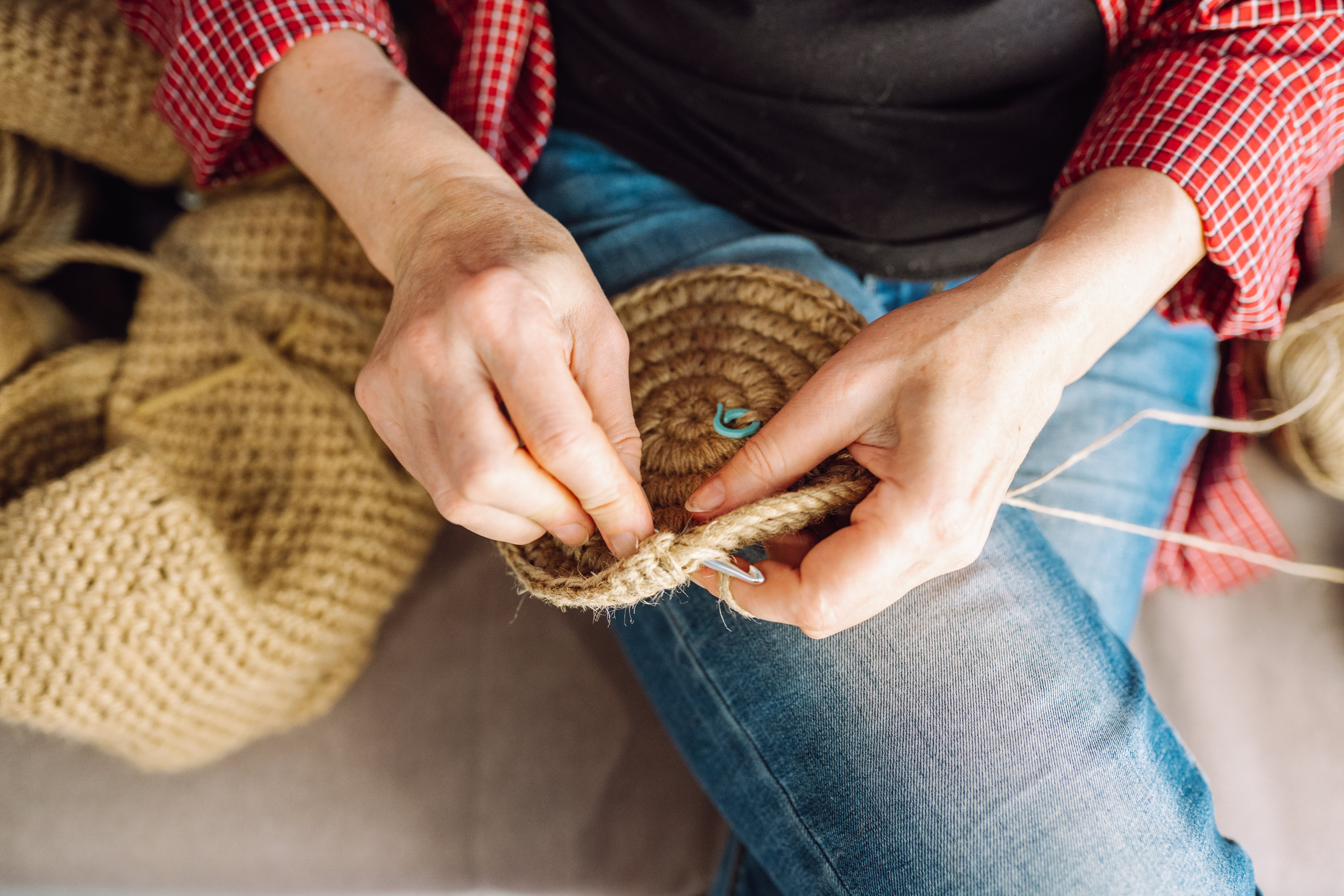 Unrecognizable Woman In Pink Shirt Knitting On Sofa At Home