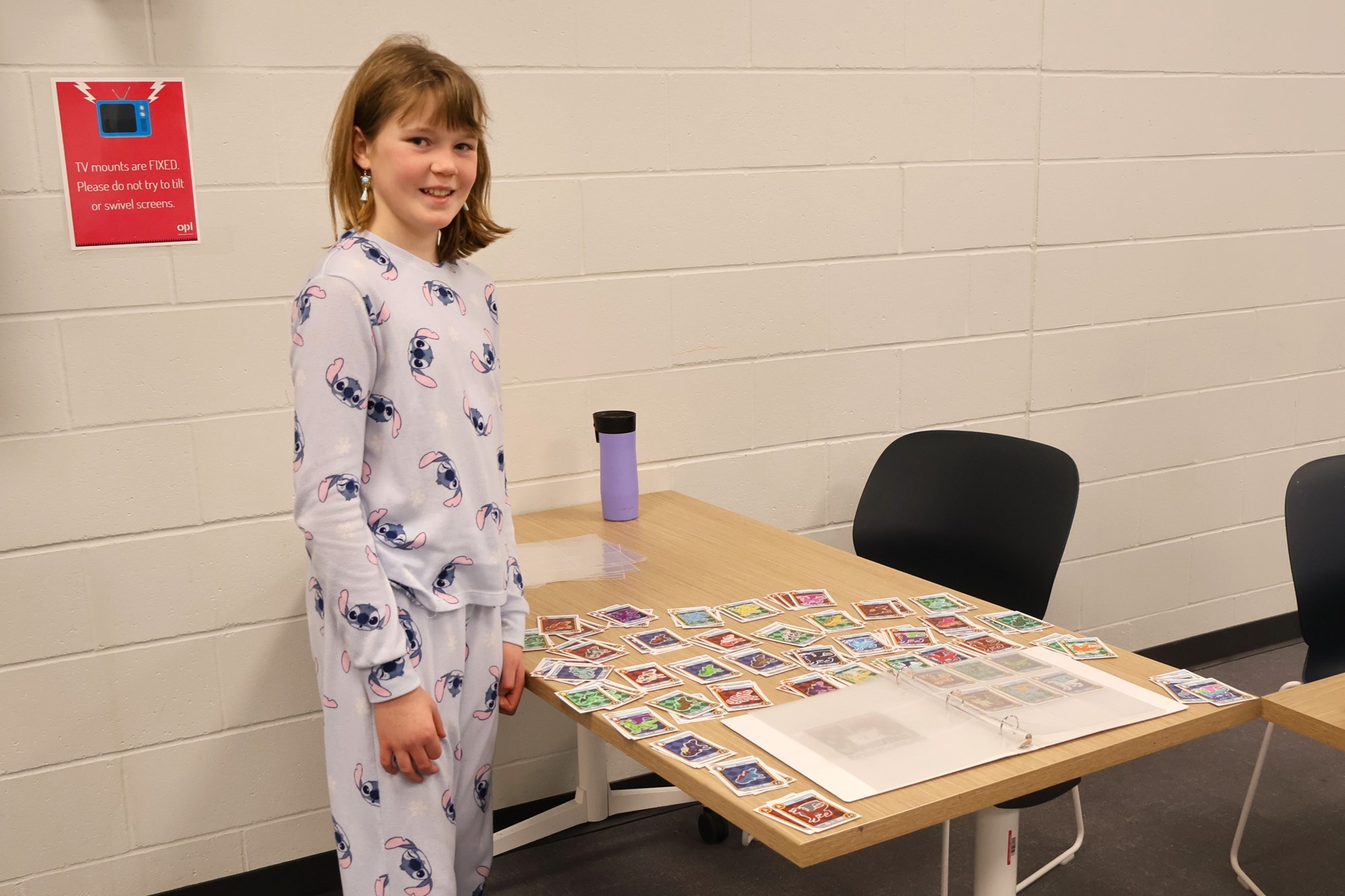 Photo of child standing in front of Reading Dragons card collection.