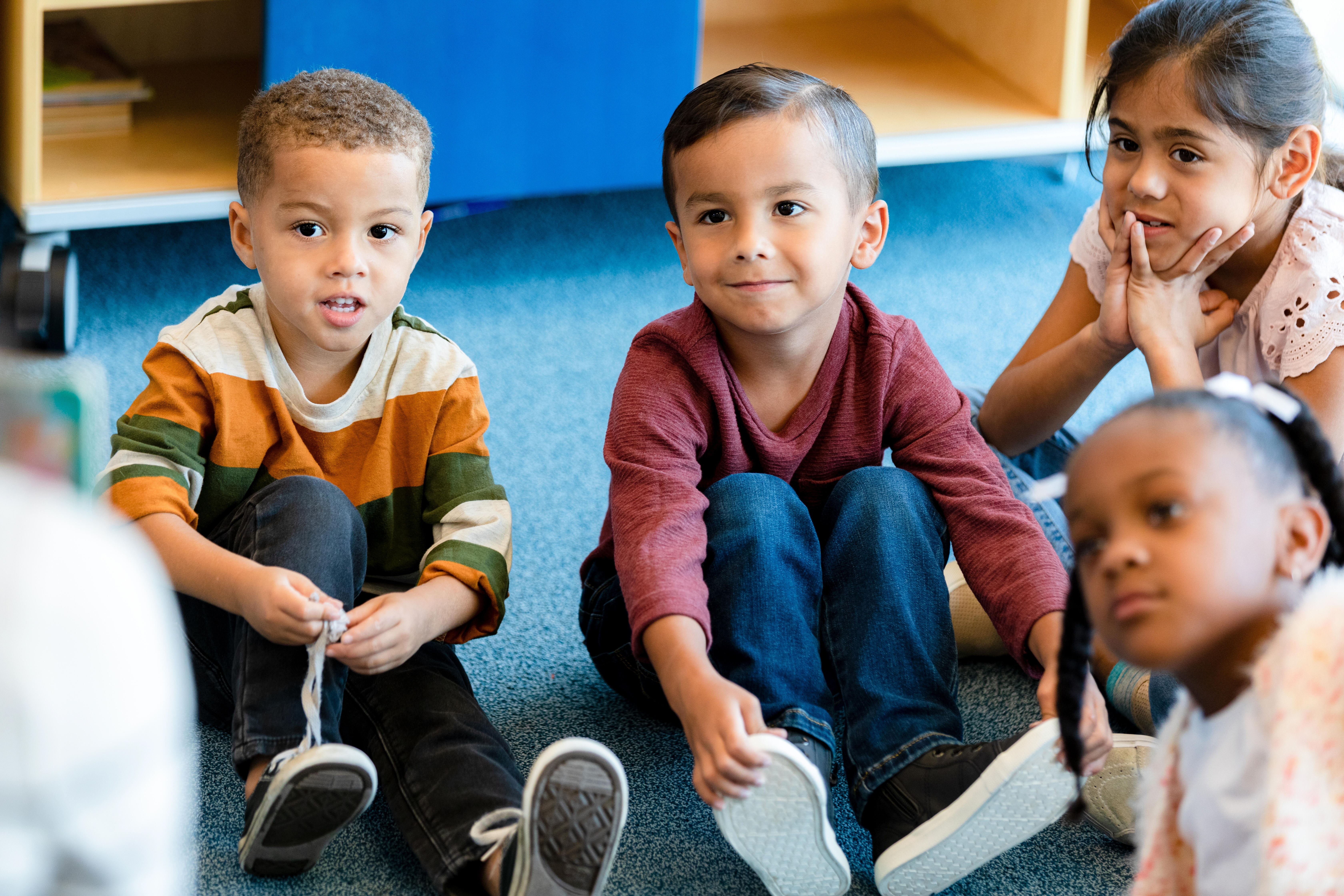 three preschool children sitting on the floor