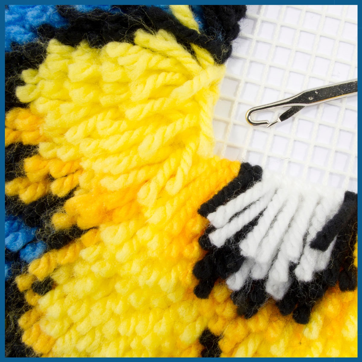 a close up image of latchhook rug, yellow and blue yarn stick out of a white base.