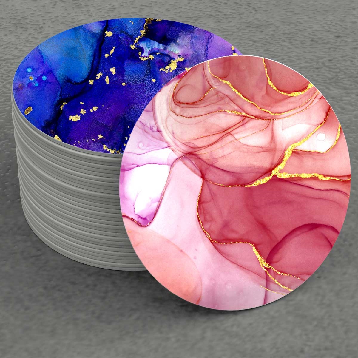 Image depicts a stack of coasters.  The top one is marbled in purple tones and there is a pink marbled coaster on its side.