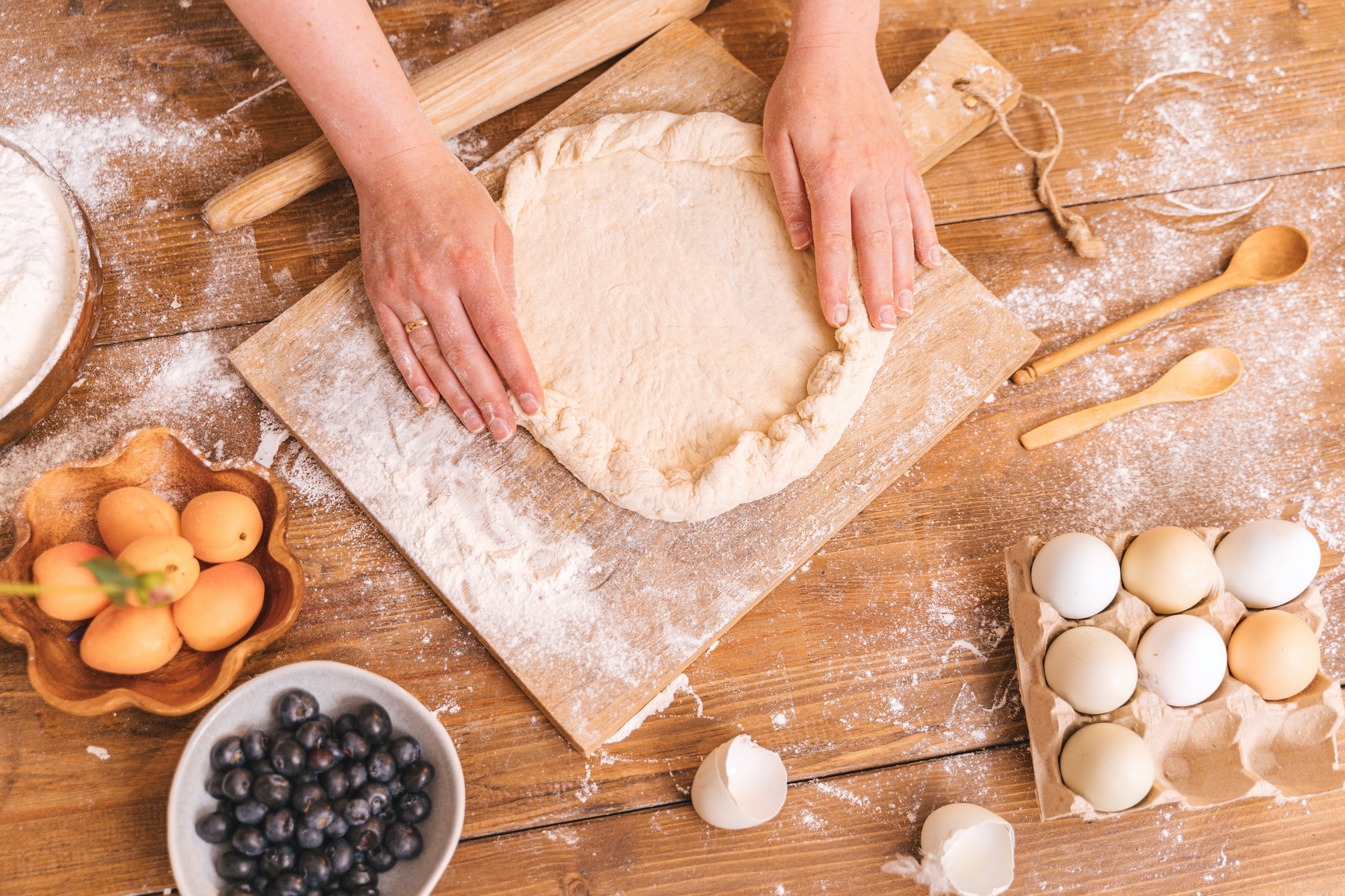ingredients to make a pie, hands rolling out pie crust