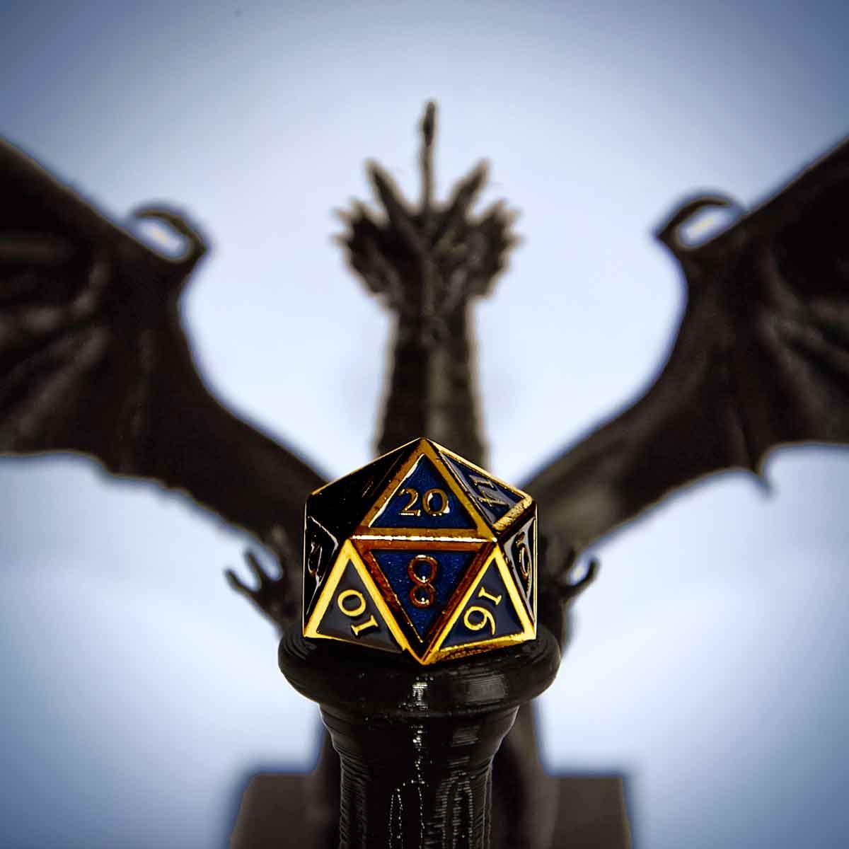 A dragon statue behind a Dungeons and Dragons dice in black and gold.