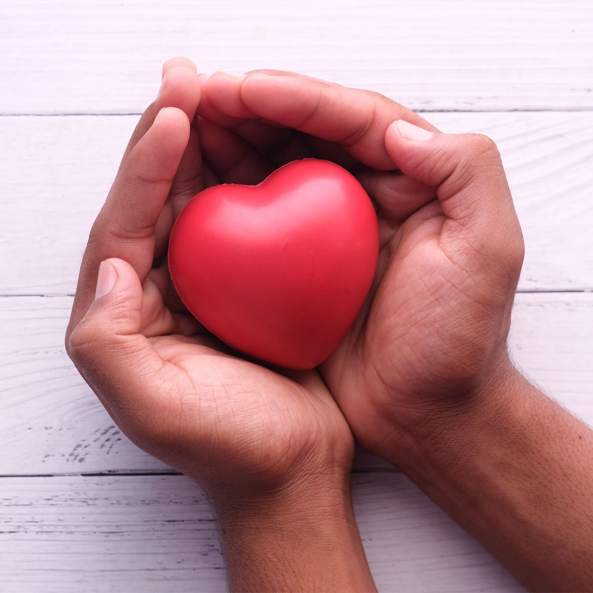 Image shows two hands cupping a red, heart-shaped stress ball.