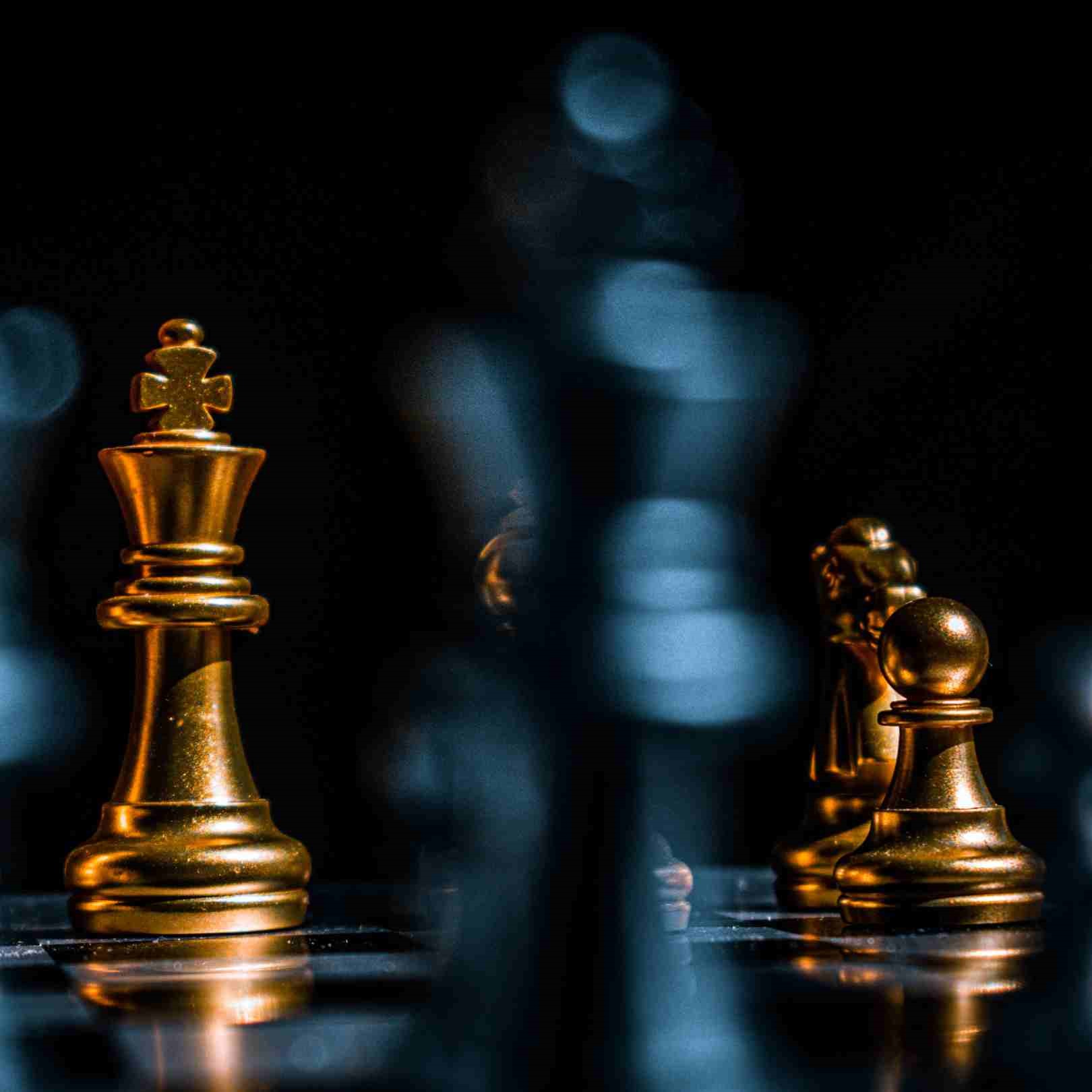 dark background with three gold chess pieces