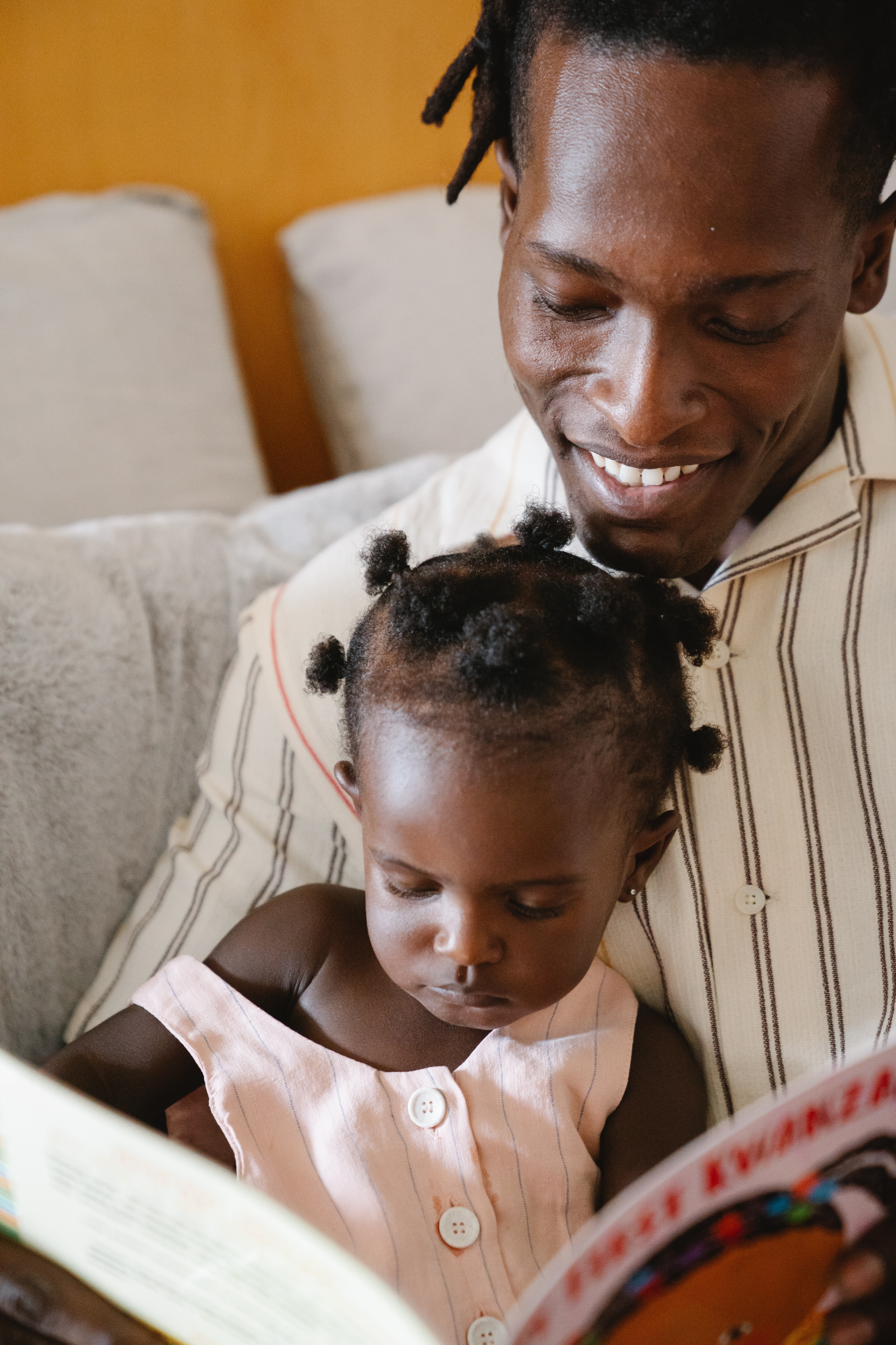 African American man holding daughter reading a book