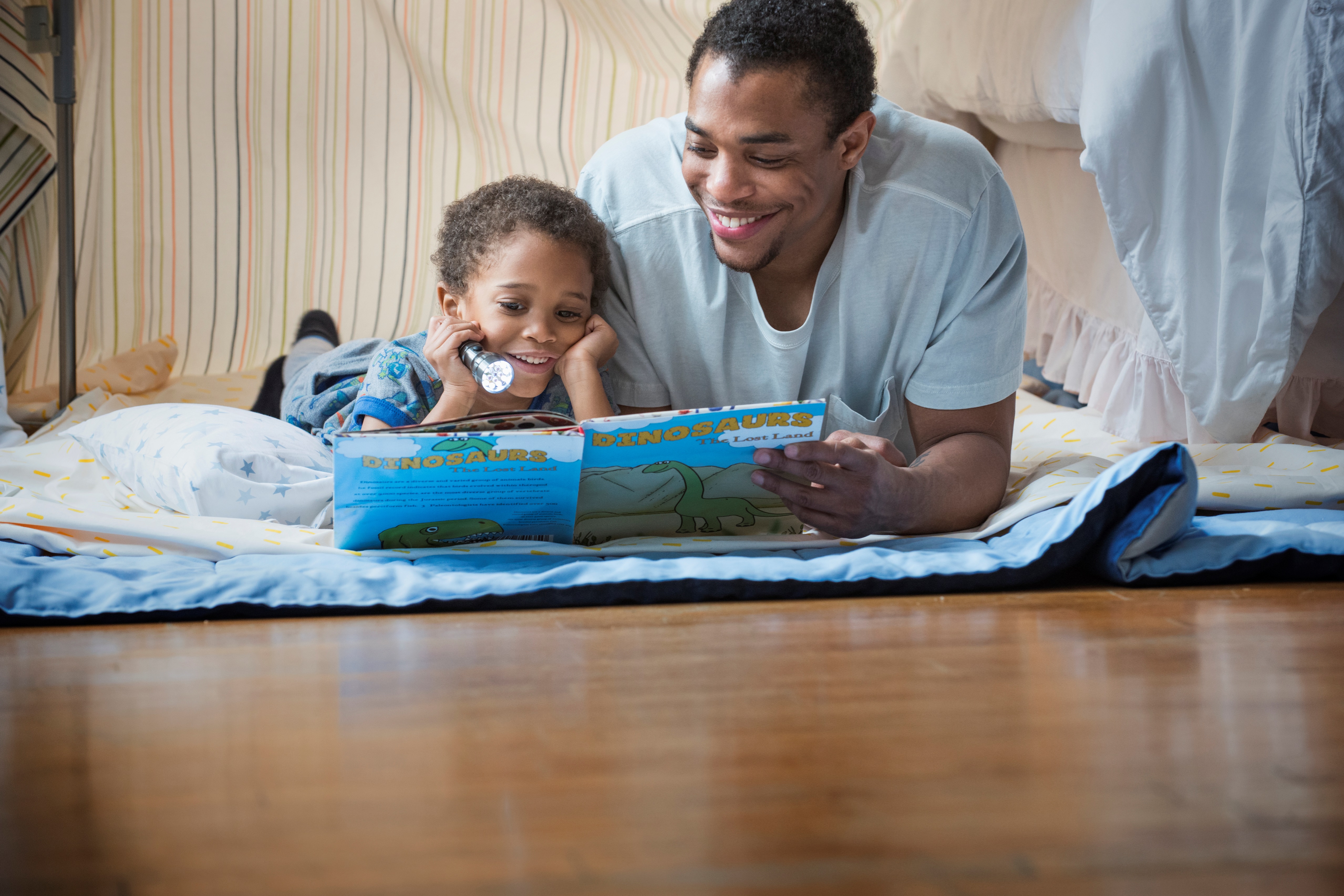 African American man reading with preschool child