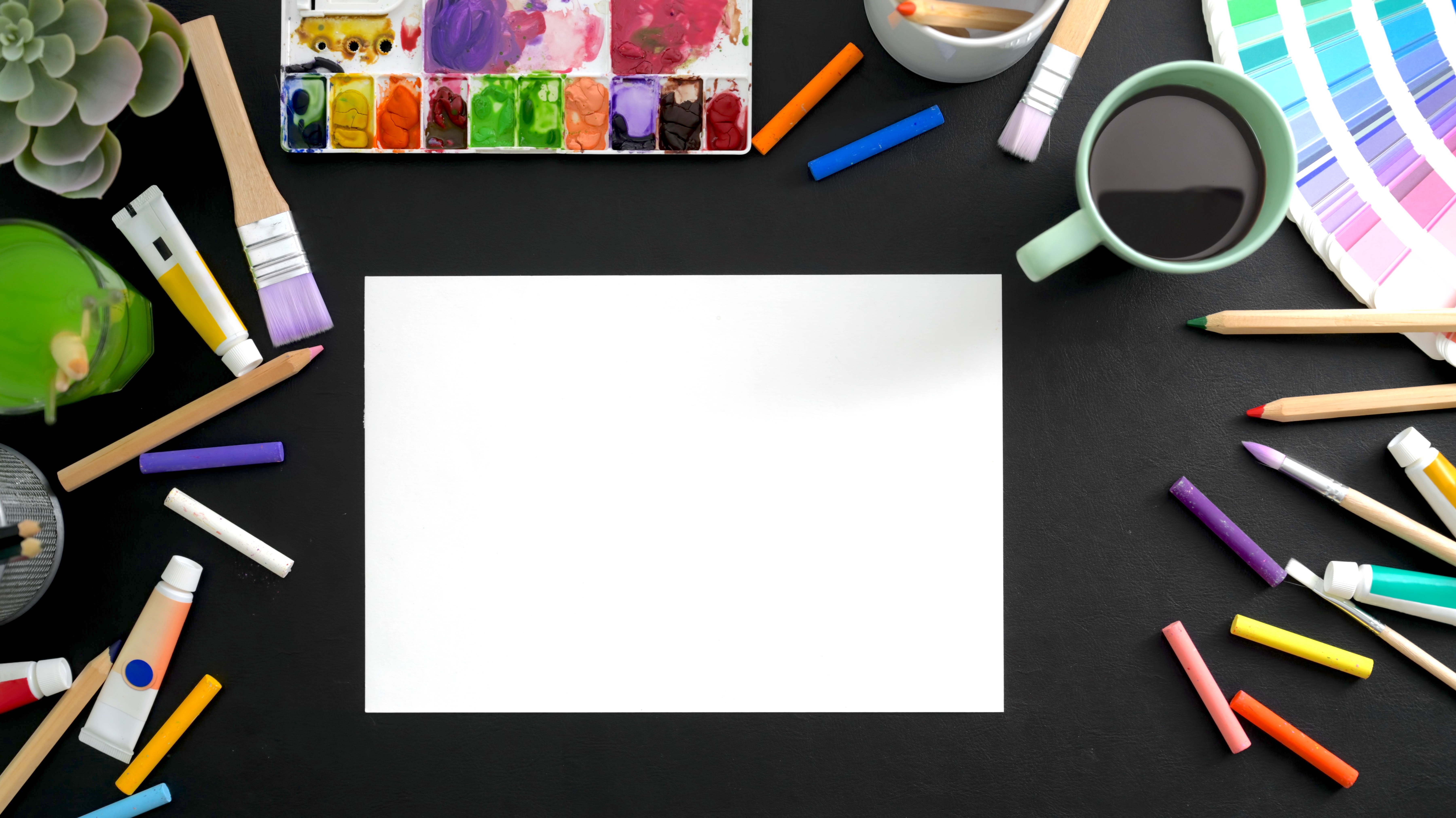 Art supplies spread out around a blank piece of paper