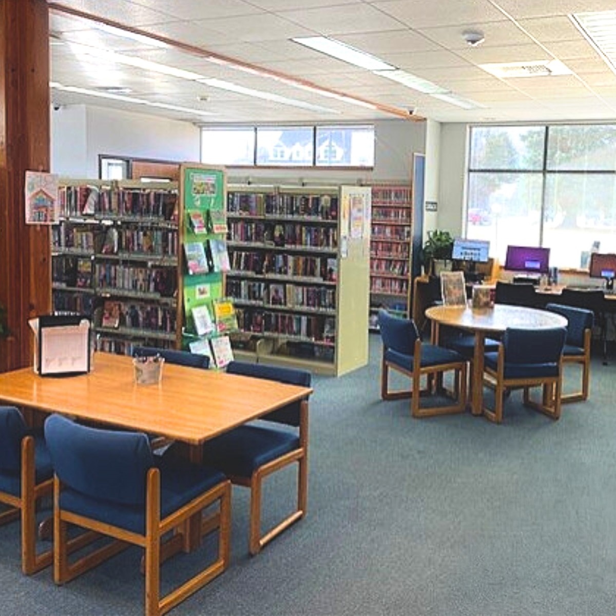 A picture of the interior of the spirit Lake library, showing book shelves, tables, and chairs.